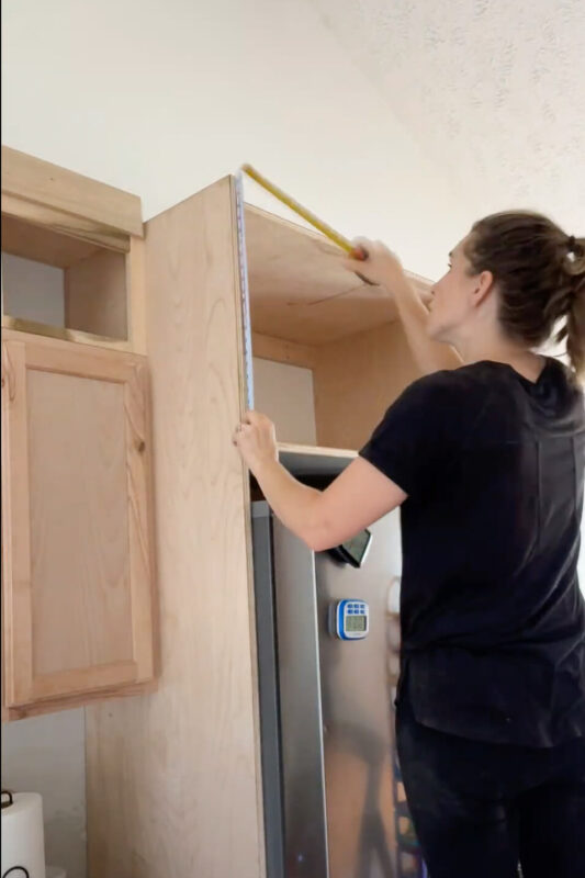 Woman measuring for cabinet trim.