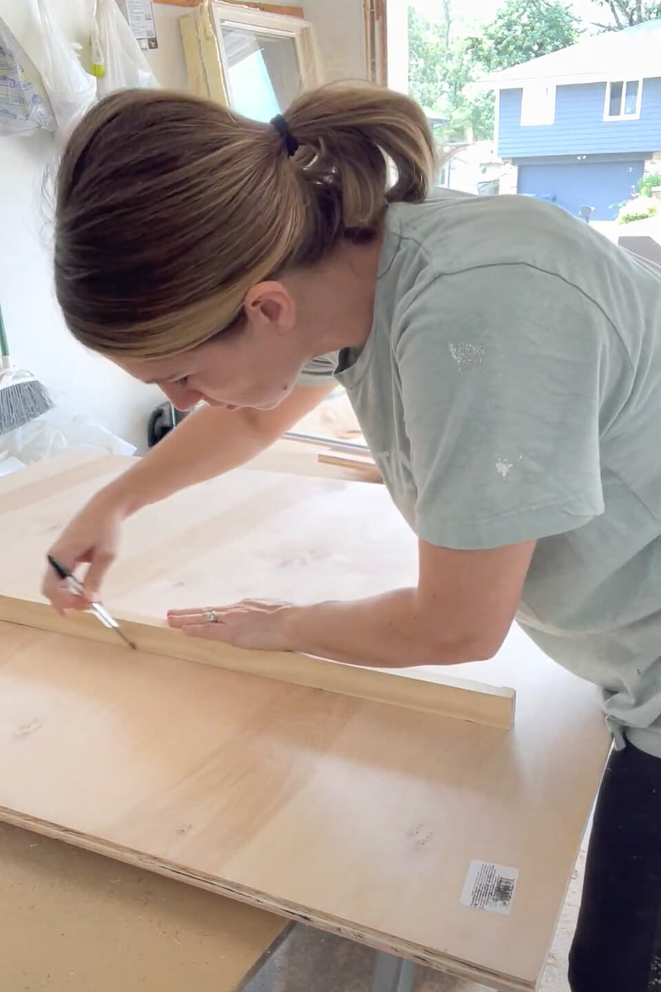 Woman measuring for cut lines while building kitchen cabinets.
