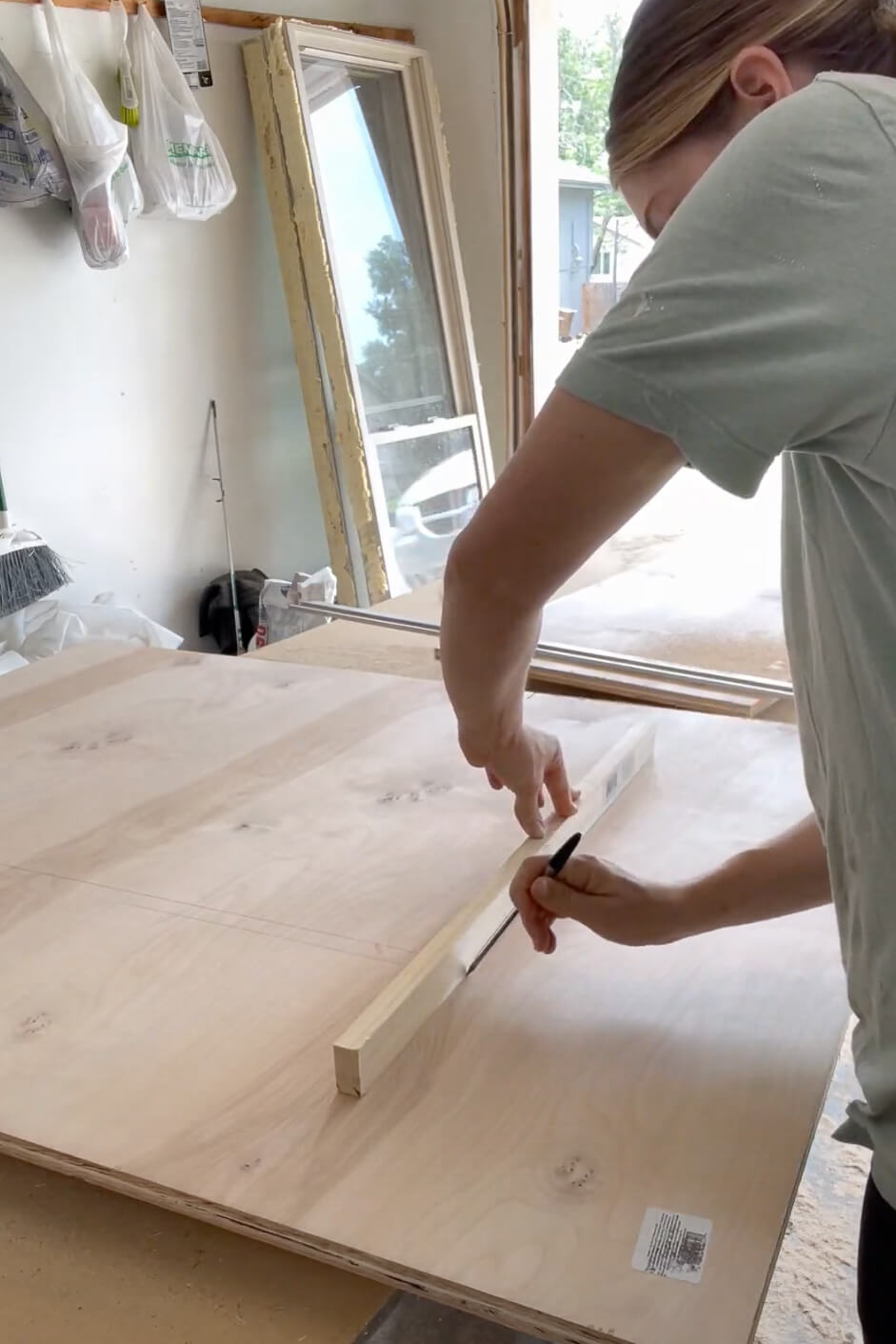 Woman measuring for cut lines while building kitchen cabinets.
