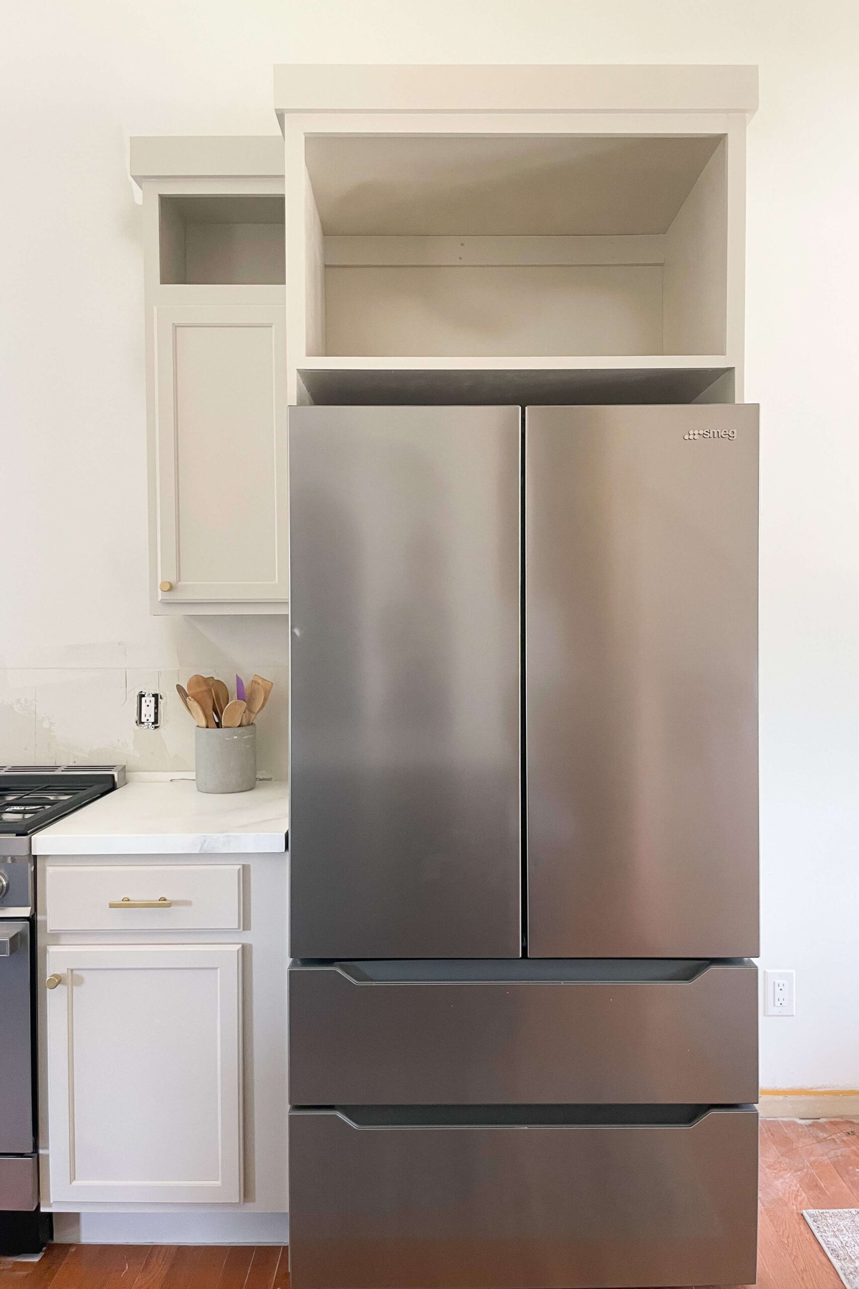 Stainless steel fridge inside of diy refrigerator cabinet.