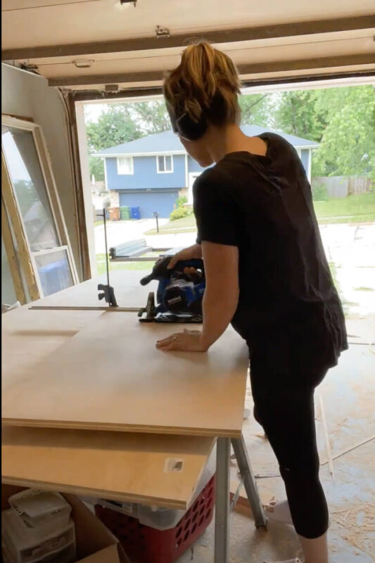 Woman cutting plywood with circular saw.