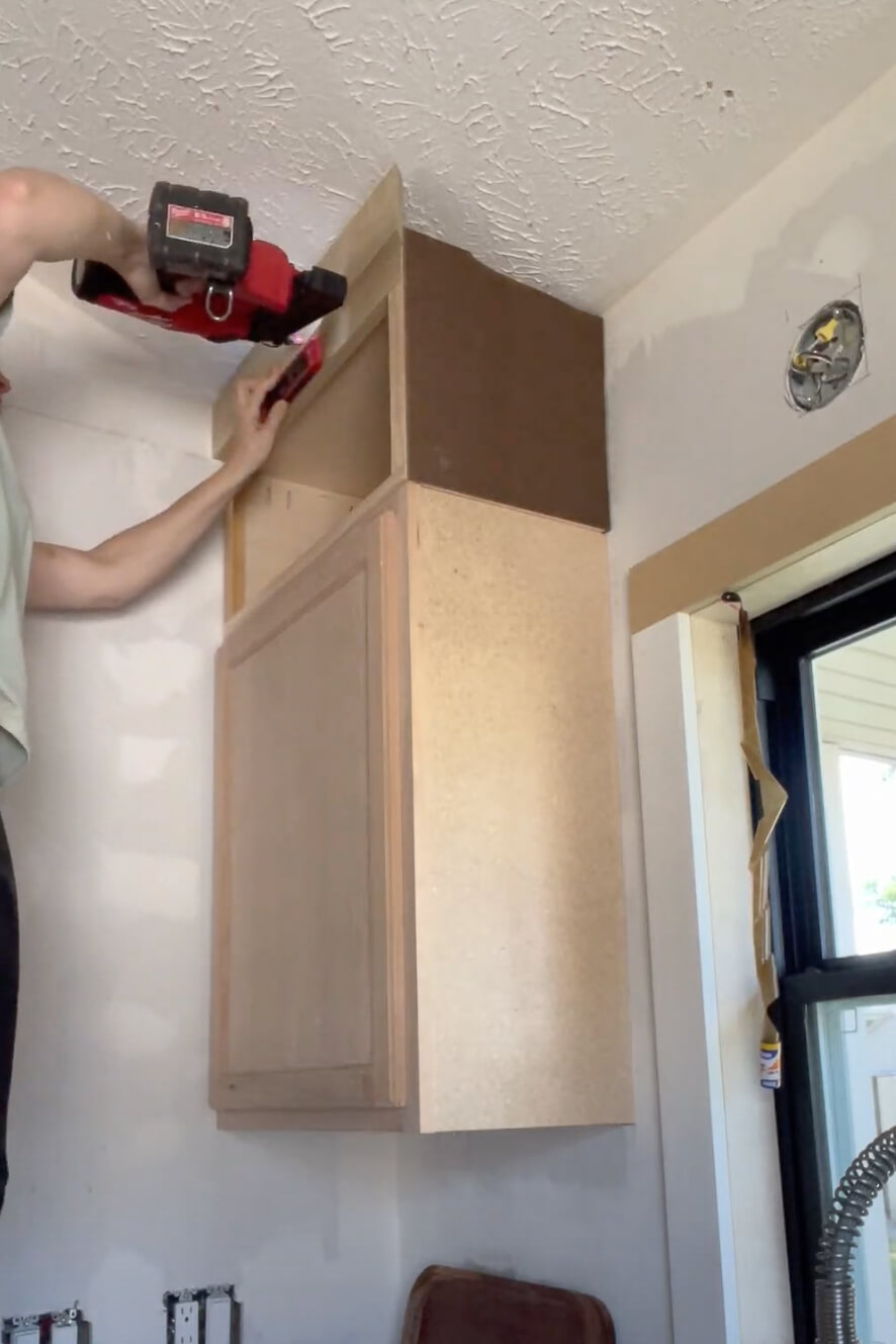 Woman adding crown molding to her kitchen cabinets.