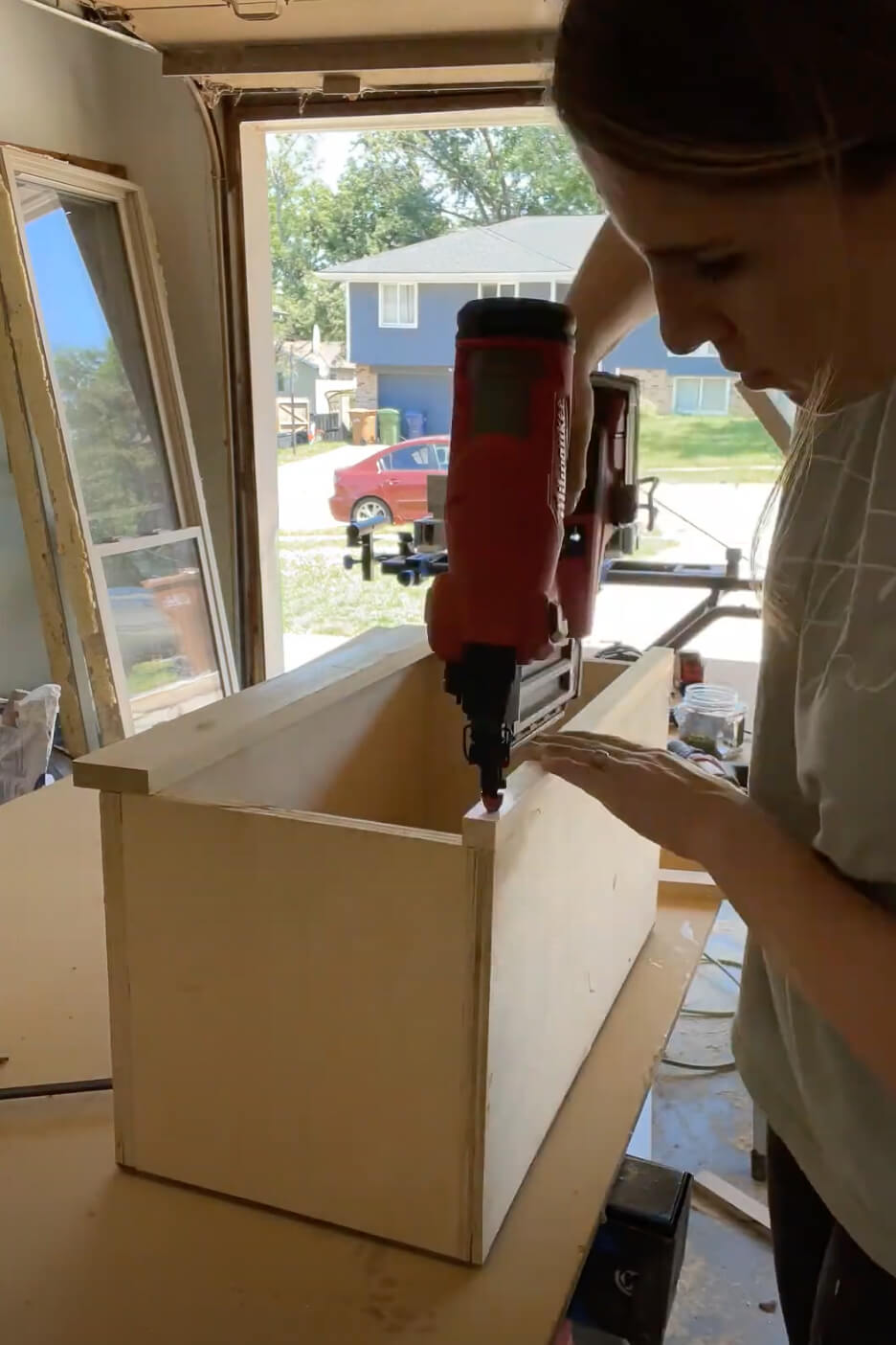 Woman using brad nailer to build a cabinet.
