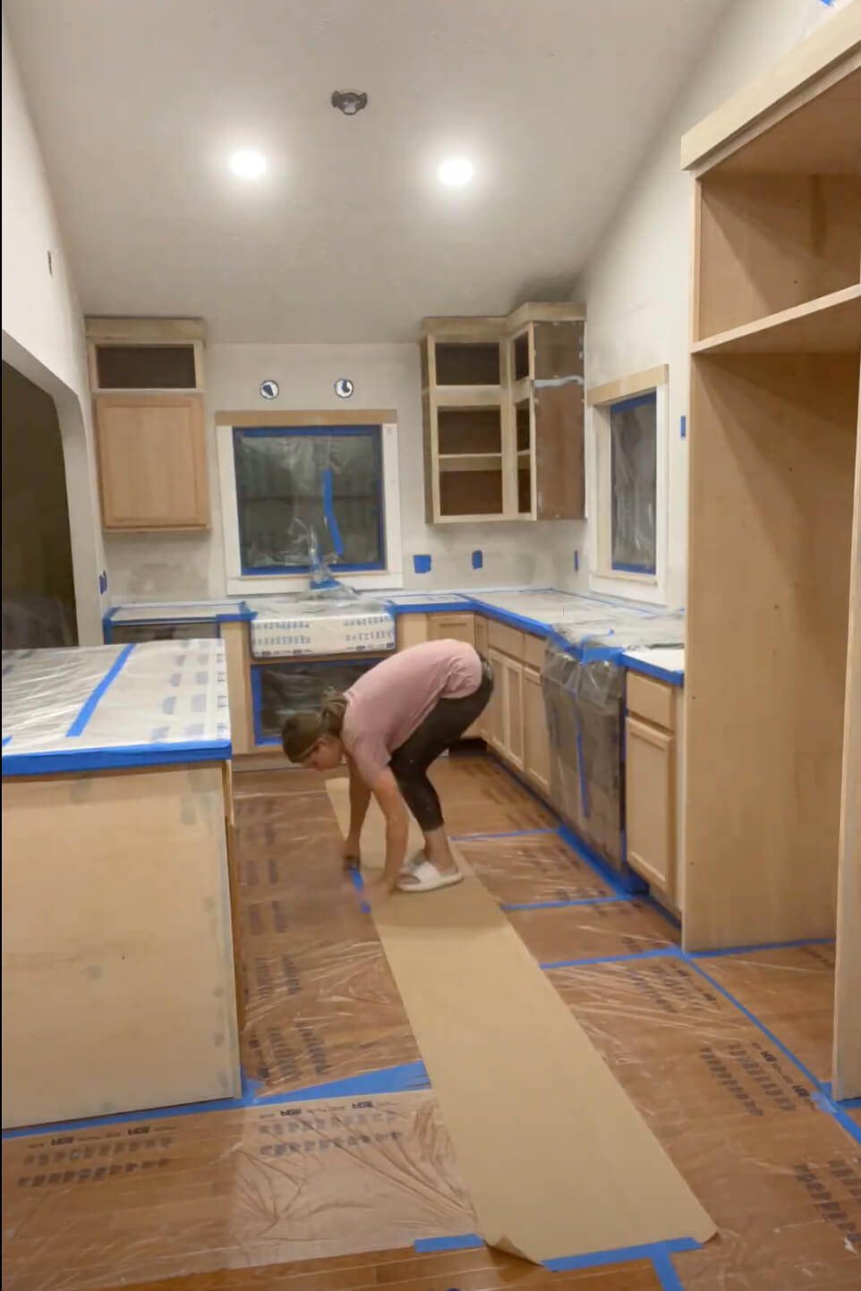 Woman prepping kitchen to paint DIY Refrigerator Cabinet.