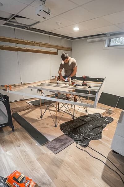 Murphy bed frame assembly in progress on portable worktable in basement guest room