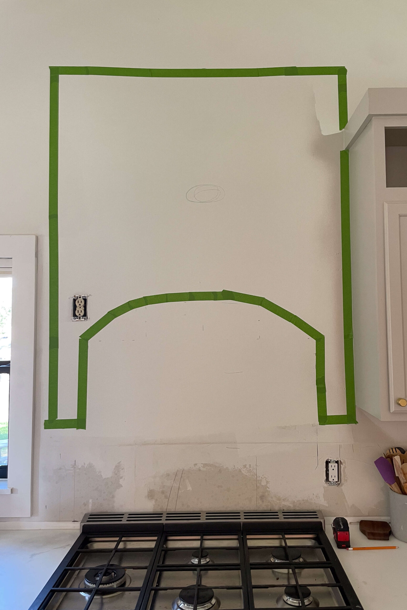 Taped out shape on a wall showing where to build a DIY stone range hood. 