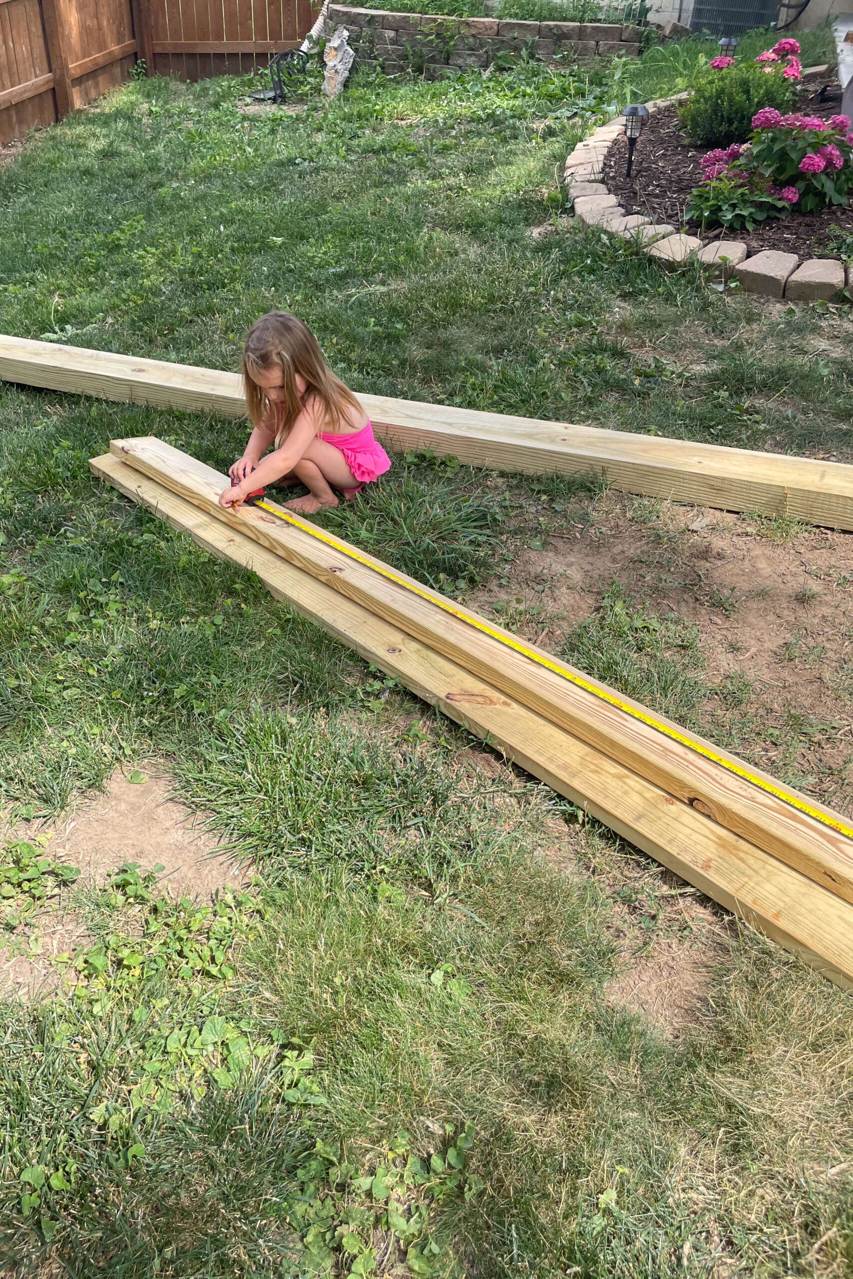 Measuring wood for building a backyard hammock stand.
