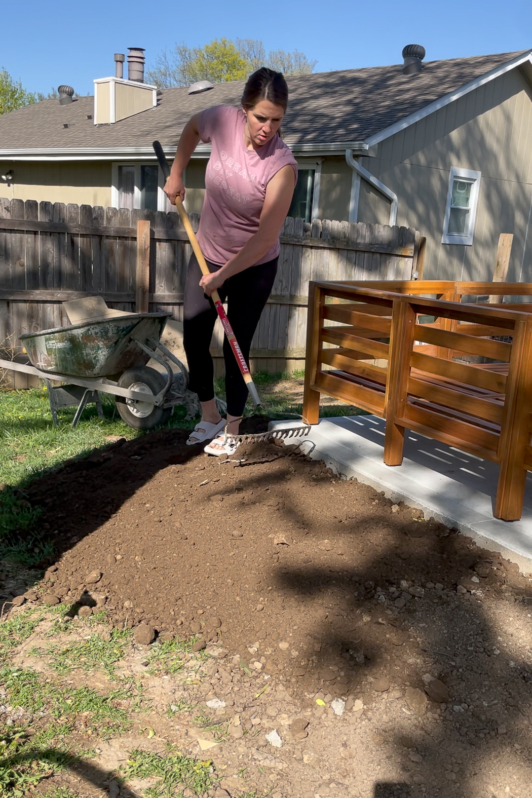 Using a stiff rake to move dirt around while making a flower bed.