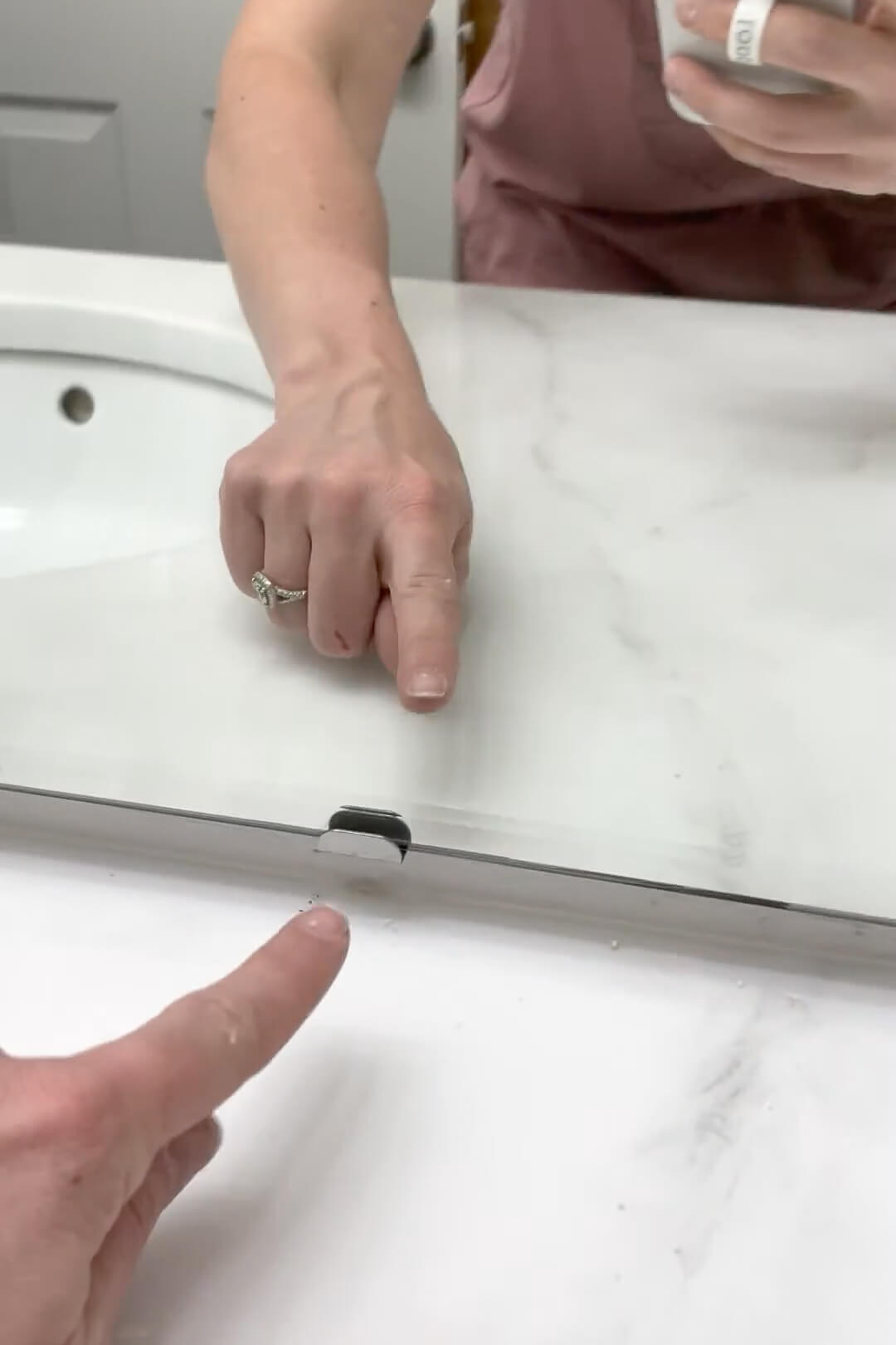 Clips are being used to hold the bathroom mirror to the wall.