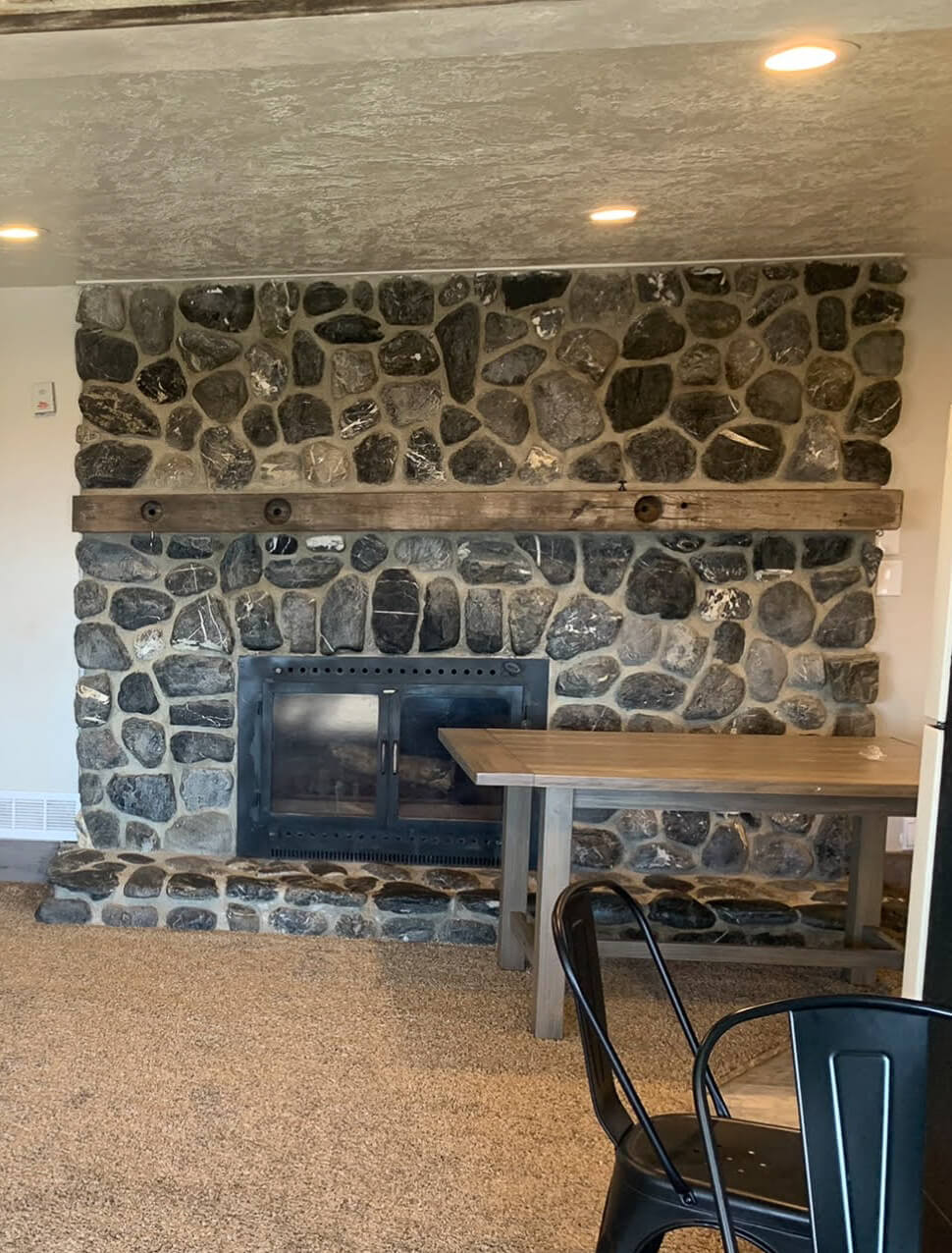 Old, dated stone fireplace before a DIY remodel.