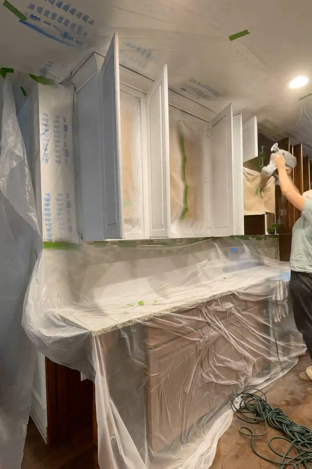 Painting kitchen cabinets with a paint sprayer and cabinet paint.