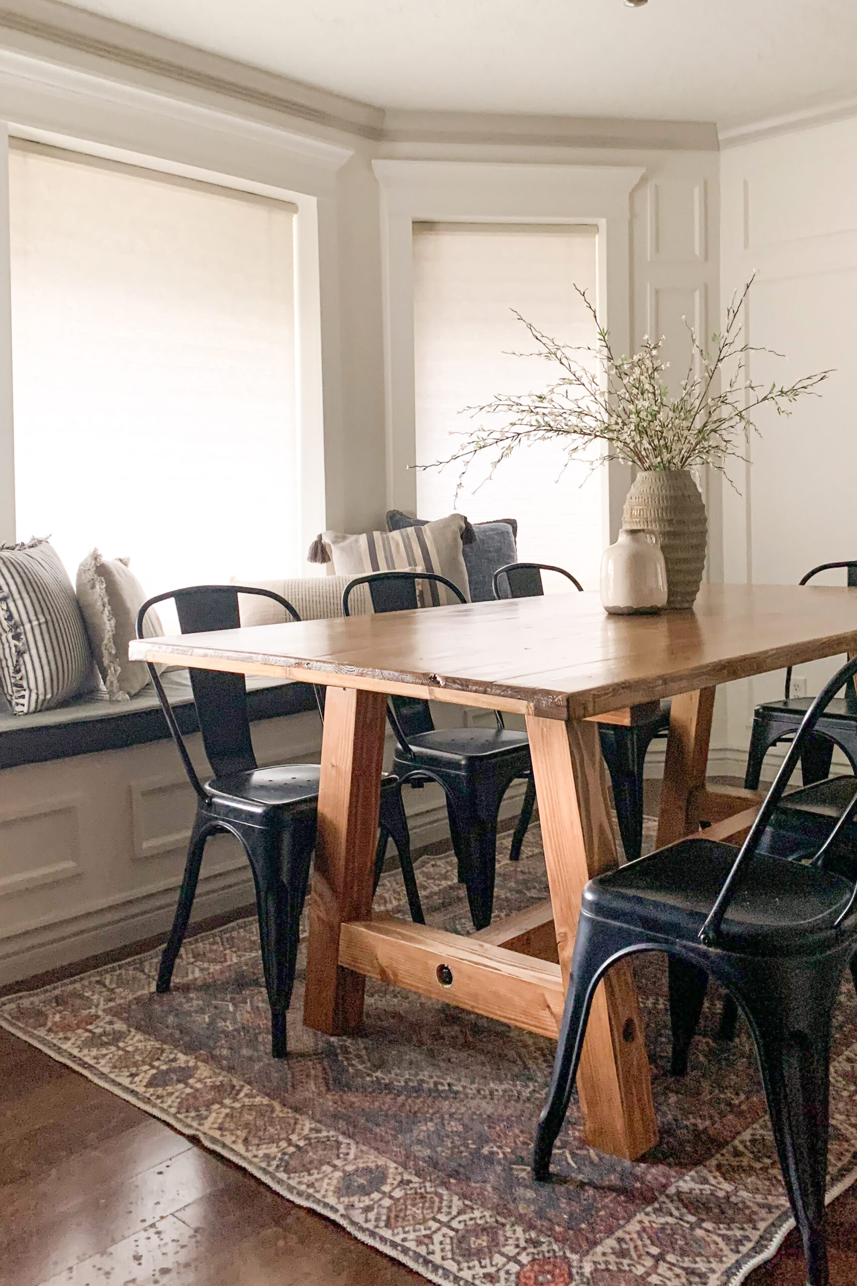 DIY built kitchen table in front of a gorgeous bay window with picture frame molding.