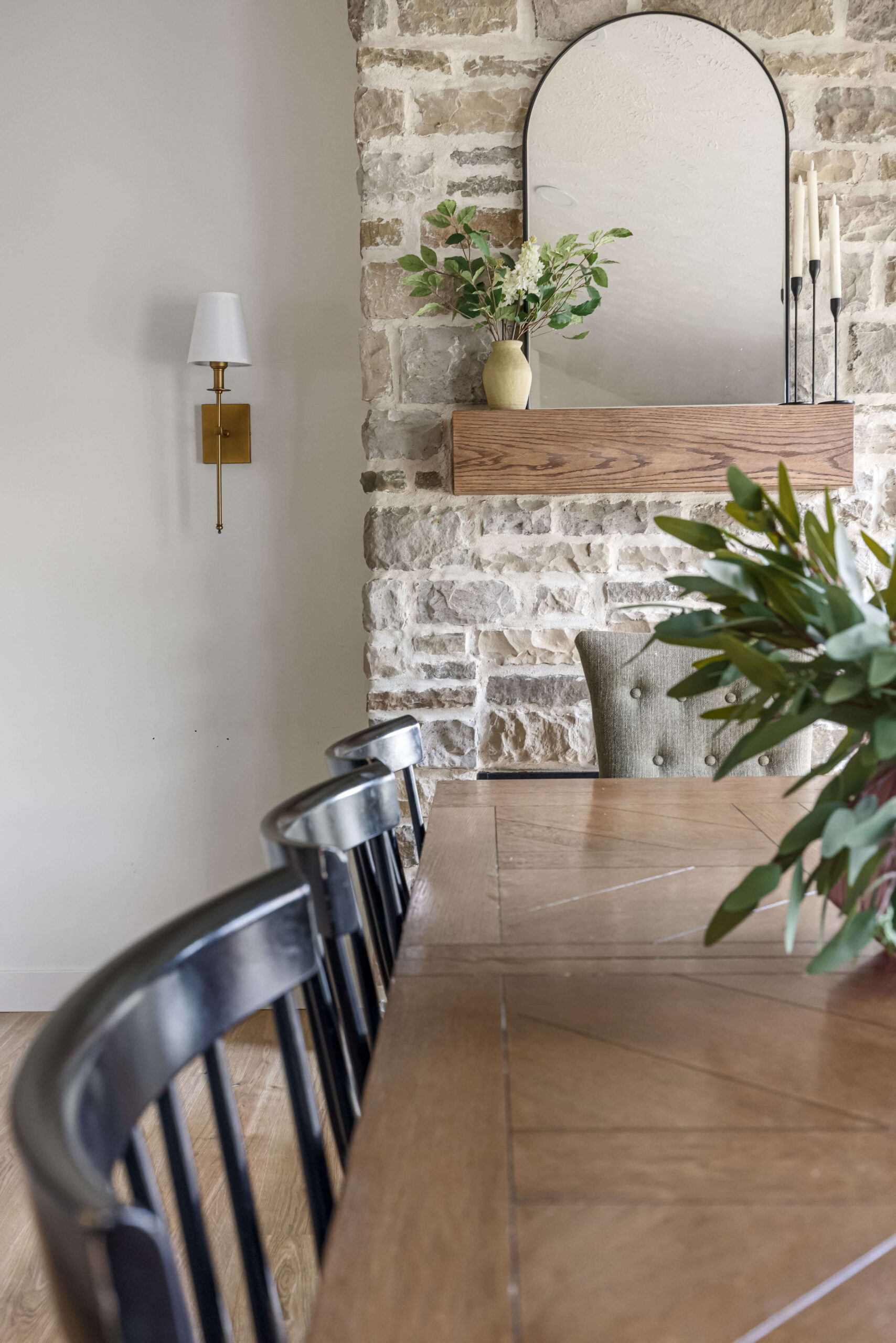 Gorgeous floor to ceiling stone fireplace next to a dining table.