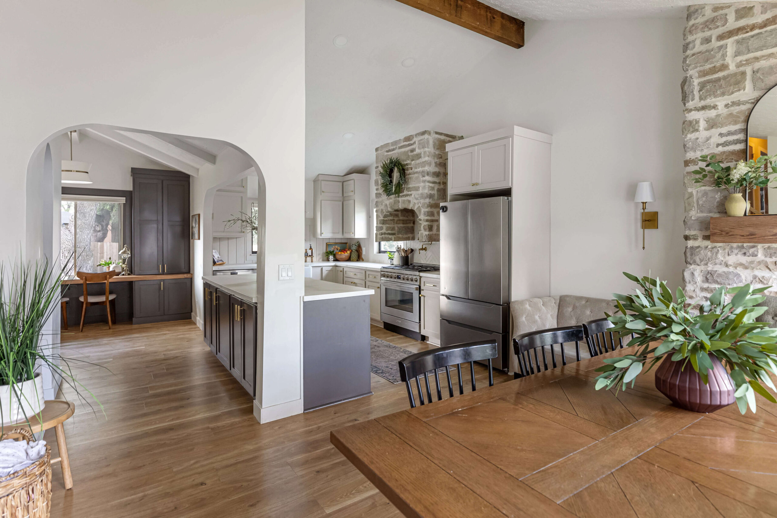 Open concept kitchen next to a dining room with huge stone fireplace.