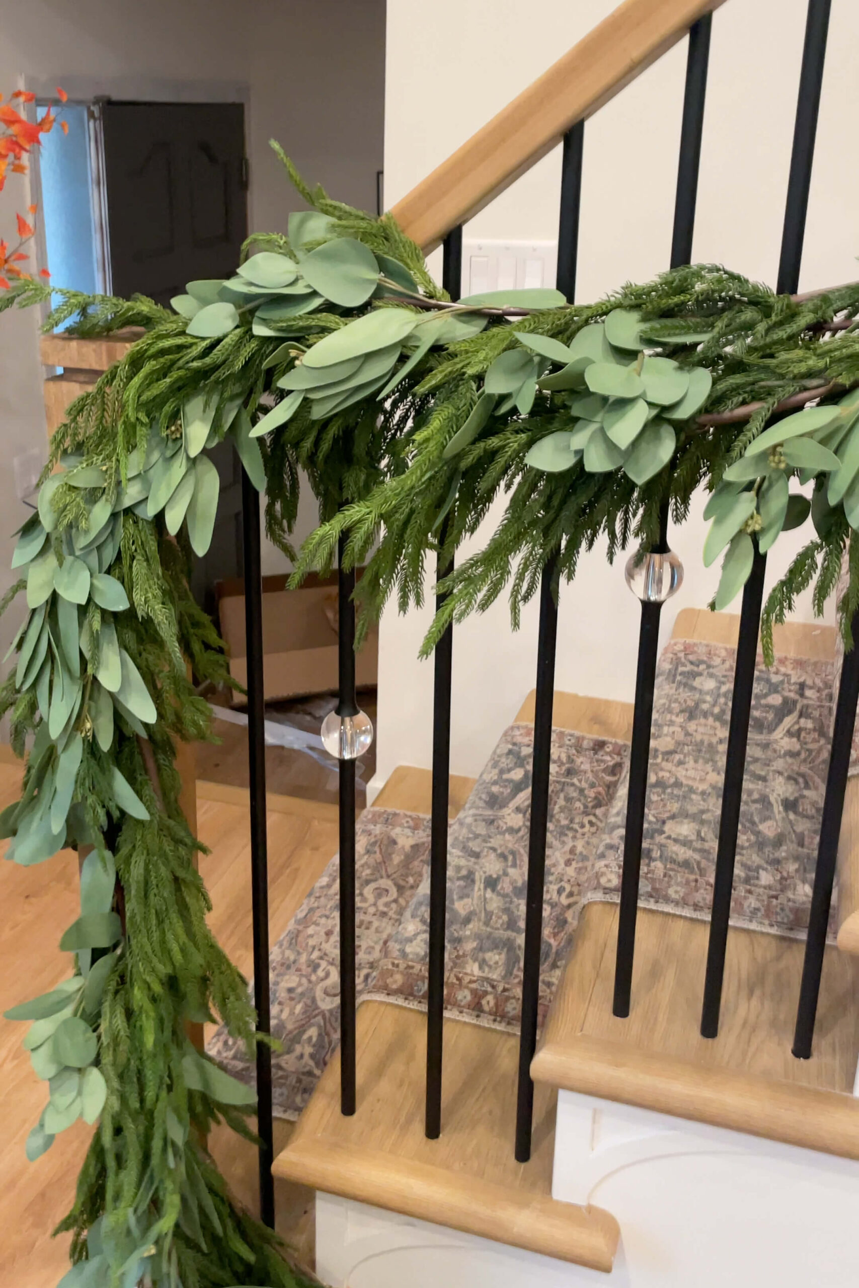 A mix of eucalyptus and pine Christmas garland on a staircase.