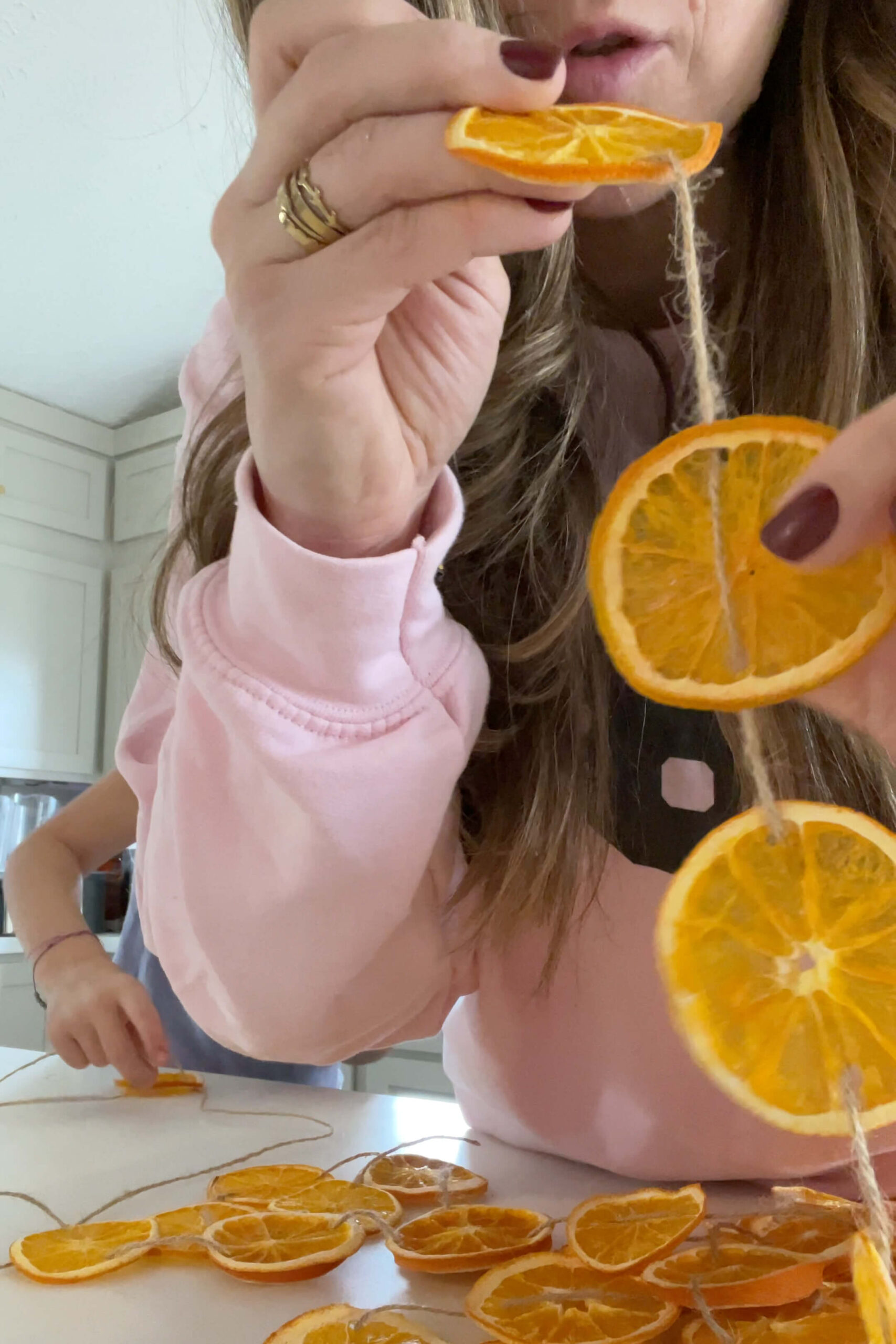 Making an orange slice garland for decorating a fireplace mantel.