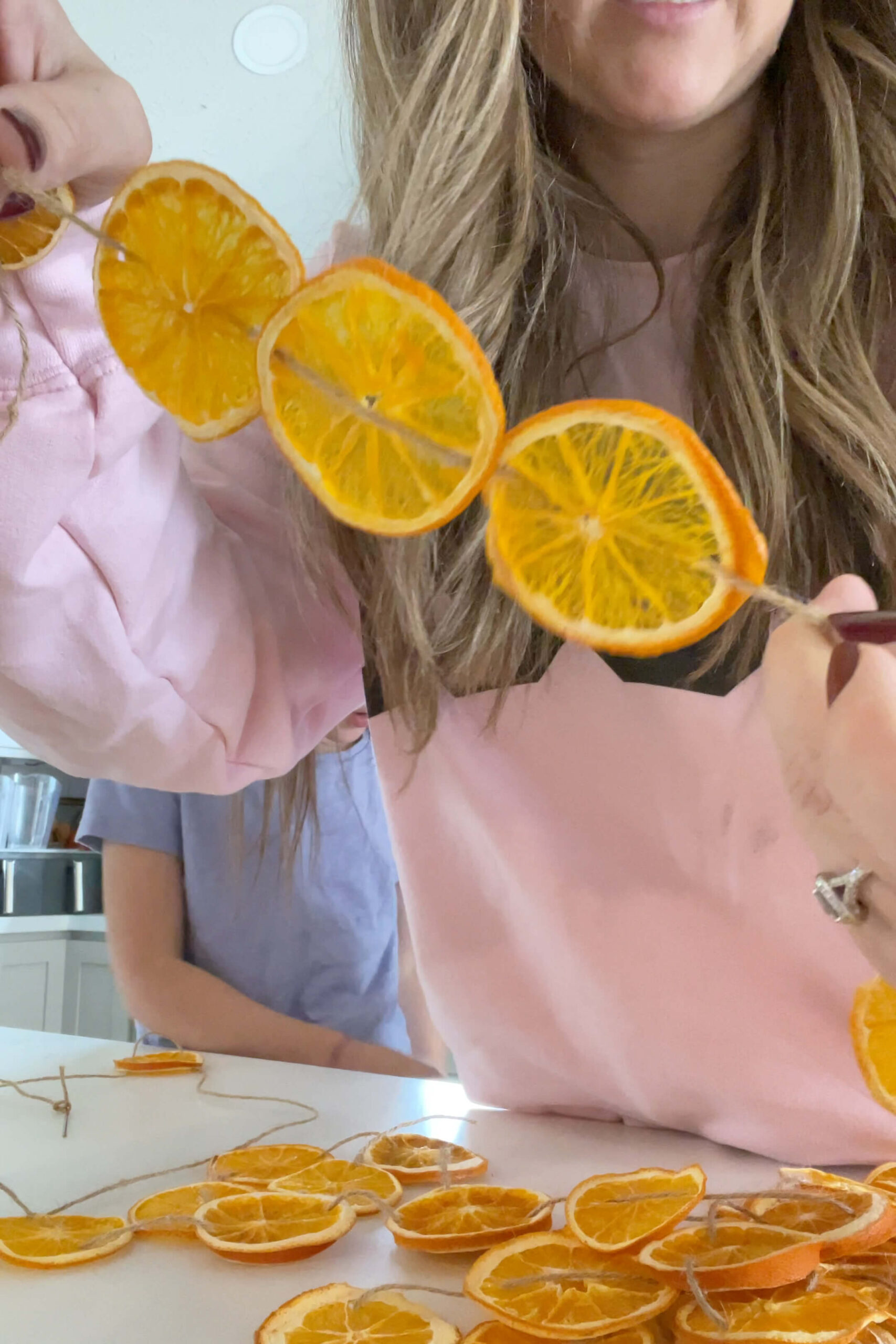 Making an orange slice garland for decorating a fireplace mantel.