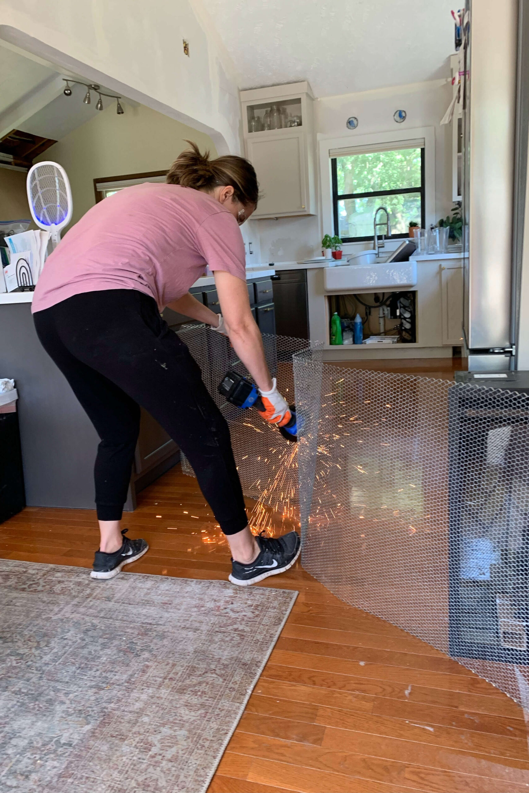 Using a grinder to cut wire mesh for a stone fireplace surround.