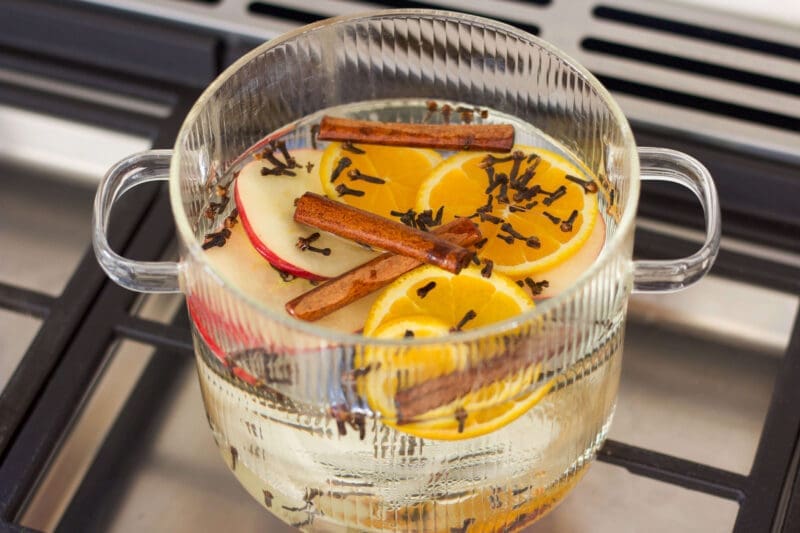 Fall simmer pot with orange slices and spices in a glass pot on the stove