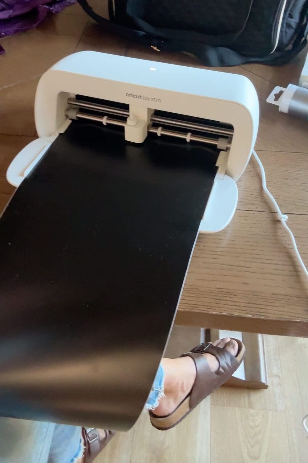 Cricut cutting black vinyl to make eyes and a smile for the sheet ghost faces.