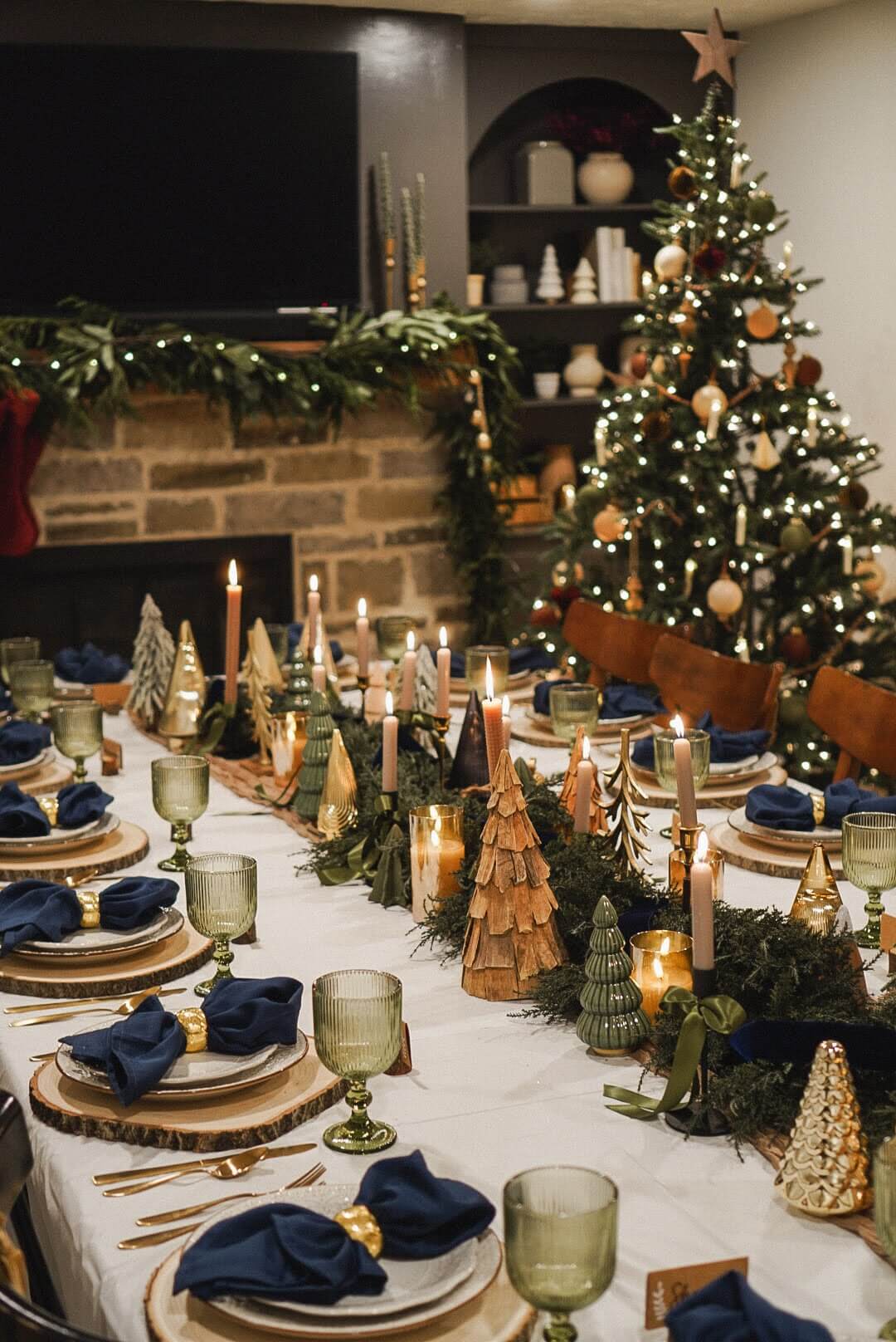 Candles and gold decorative Christmas trees adorn a Christmas tablescape, adding warmth and elegance to the holiday setting.