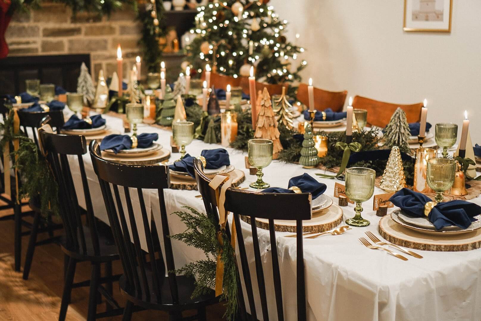 Full view of a festive Christmas tablescape featuring Christmas tree decorations, candles, and a beautifully decorated Christmas tree in the background.