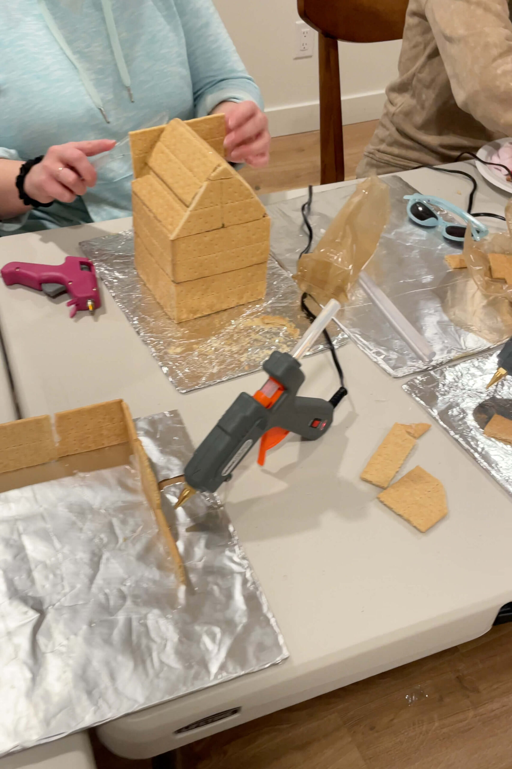 Using a hot glue gun to assemble a gingerbread house.