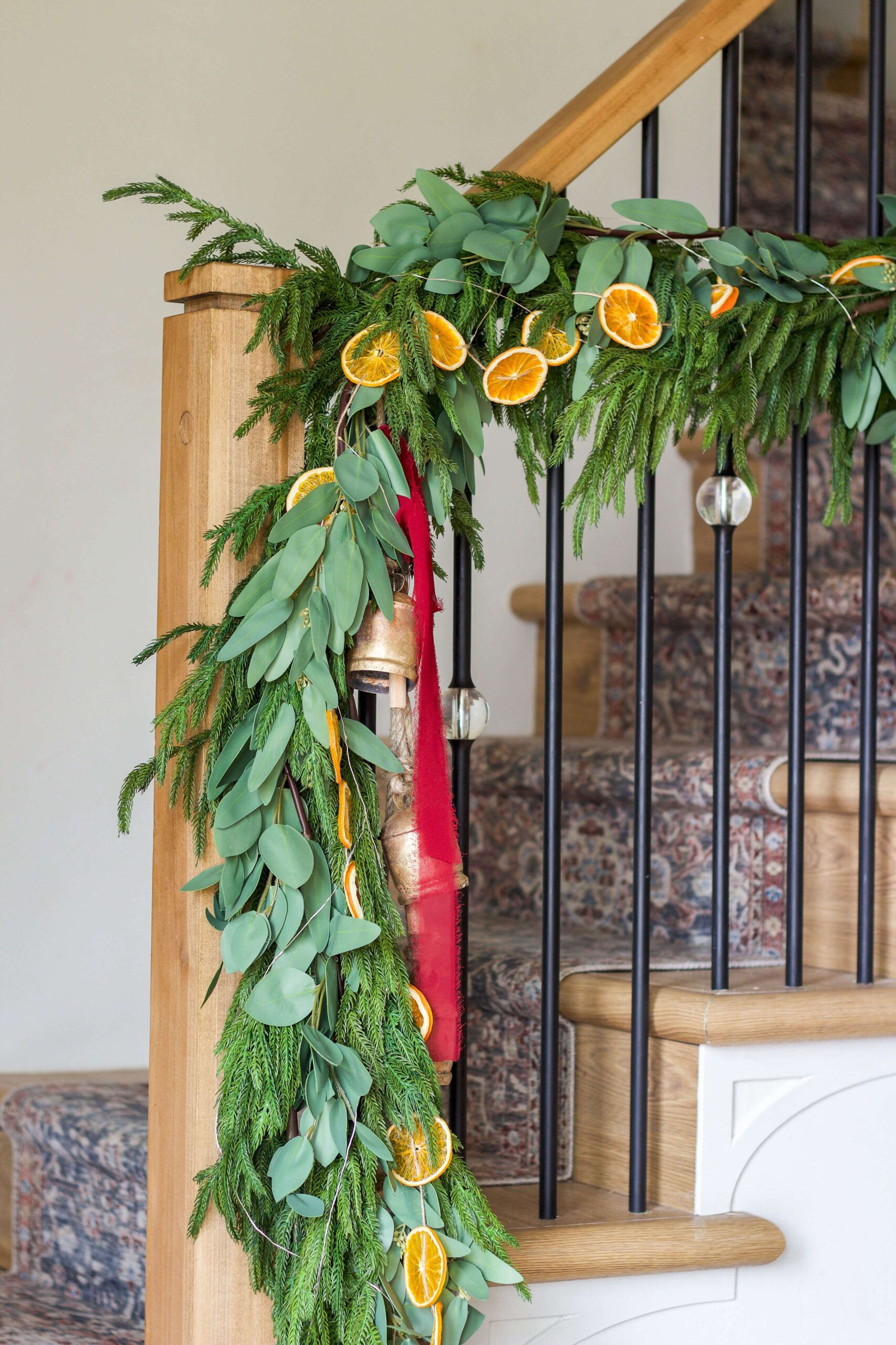 Staircase decorated with a Christmas garland featuring fresh greenery and dried orange slices.