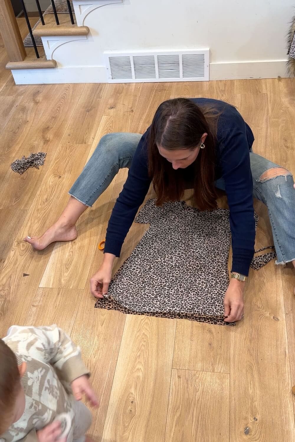 Laying out and shaping a leopard-print tunic on the floor before hemming.