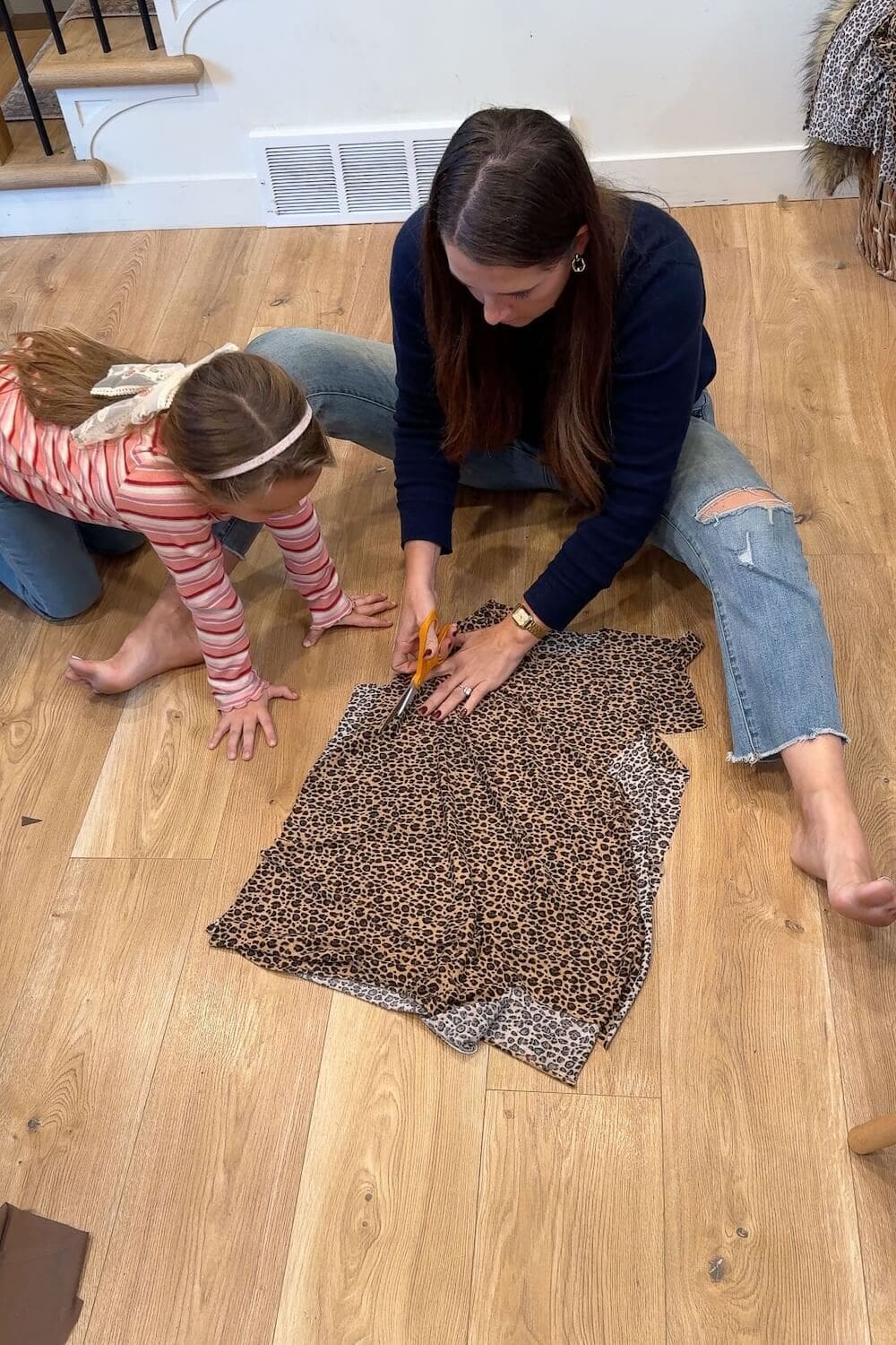Cutting the side seam of a child’s leopard-print tunic while she watches.