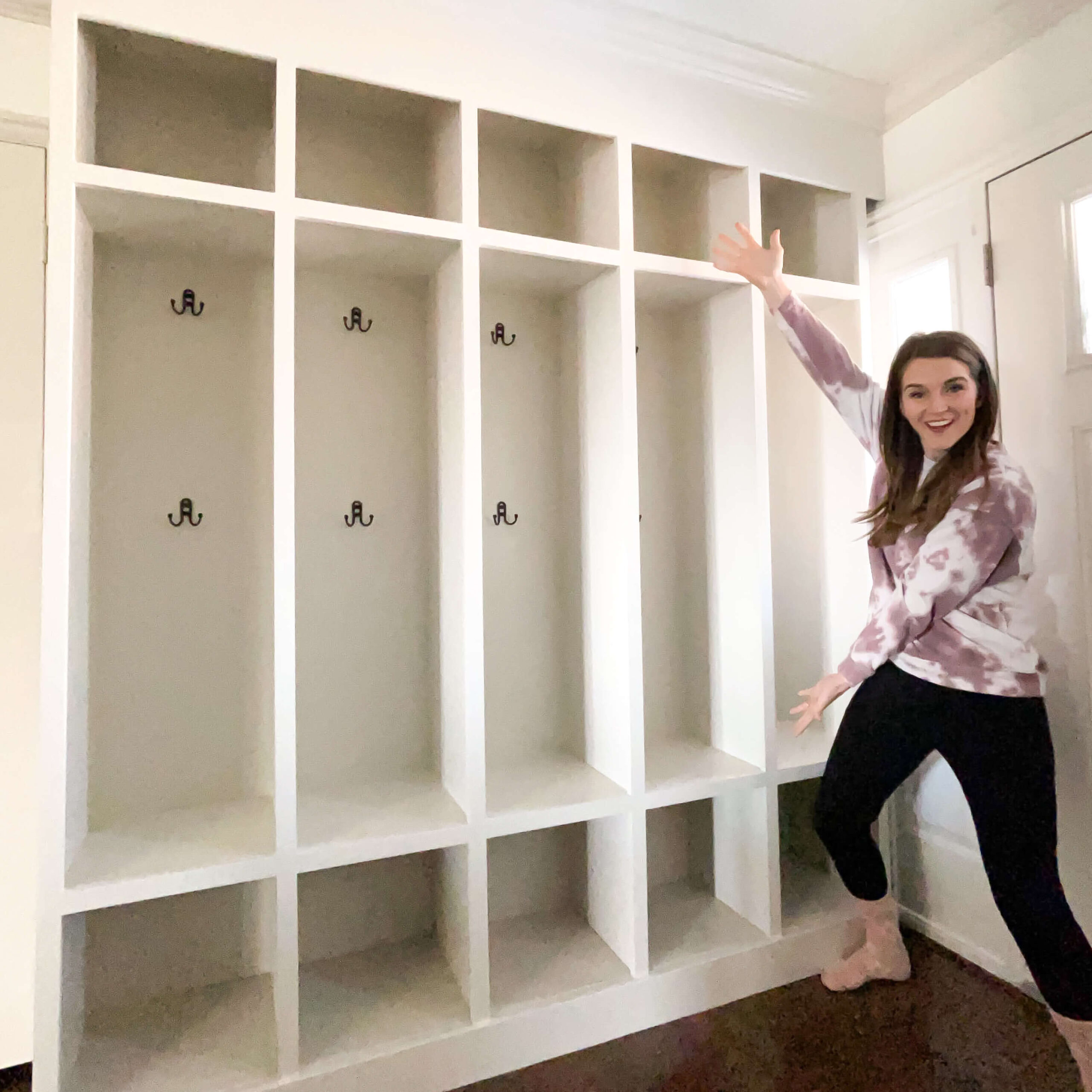Finished DIY built-in mudroom lockers with individual cubbies, coat hooks, and overhead storage. Painted white and ready for organizing jackets, backpacks, and shoes.