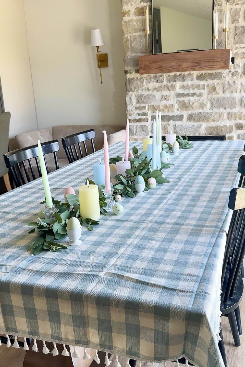 Spring tablescape with blue gingham tablecloth, woven placemats, and eucalyptus garland down the center