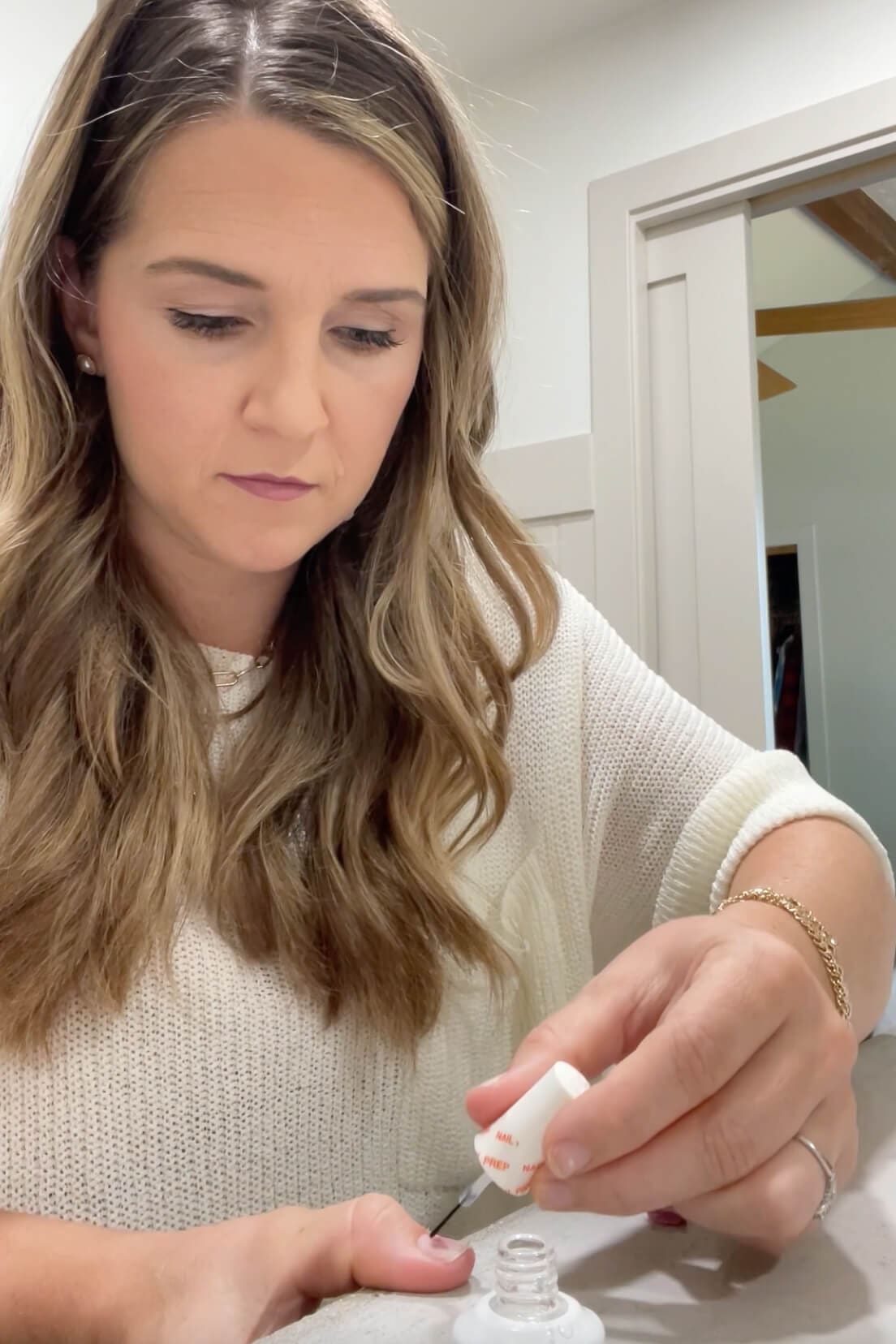 Applying a nail bonding solution to clean natural nails before starting a DIY manicure at home.