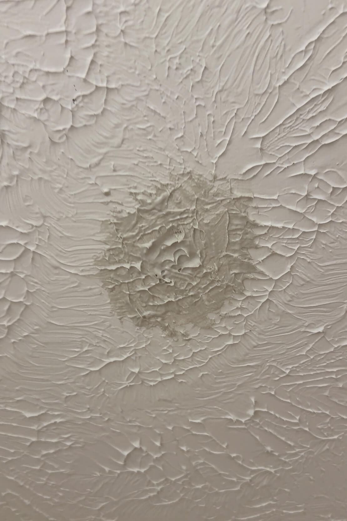 Textured ceiling with dried joint compound patch before final paint touch-up