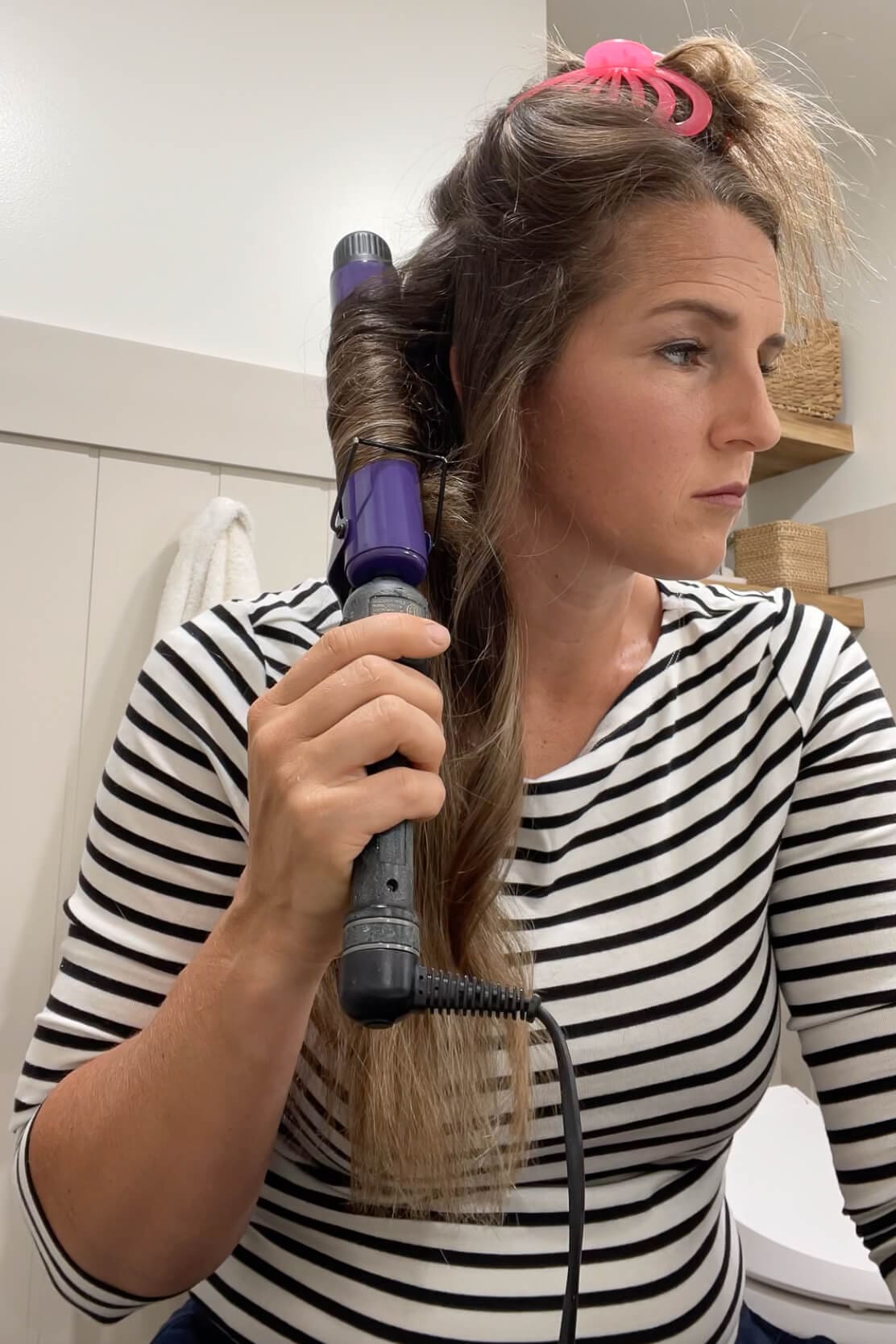 Styling freshly layered hair with a curling iron to create soft waves that show off the cut.