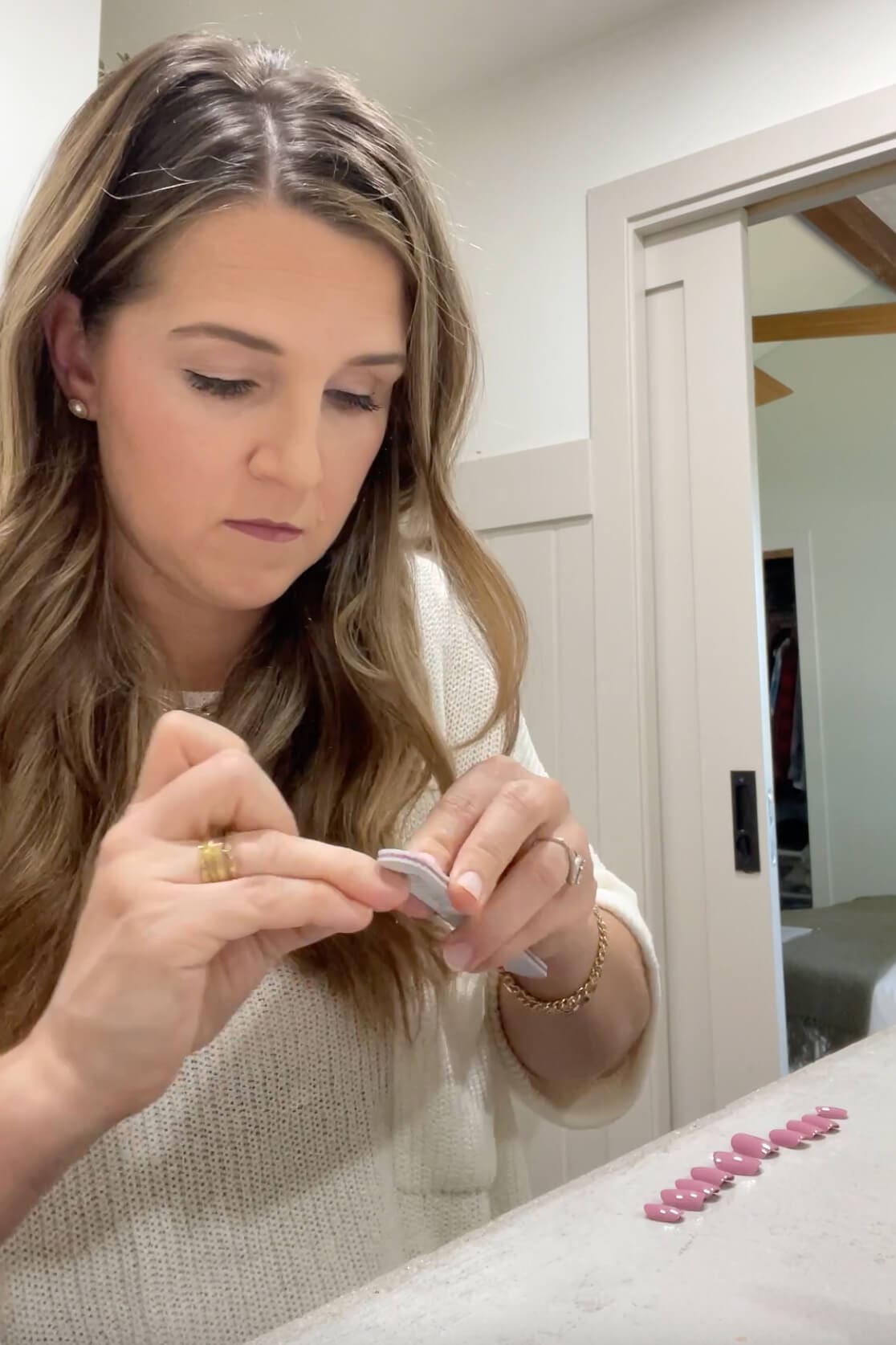 Filing natural nails as part of the prep process before applying Kiss Impress press-on nails at home.