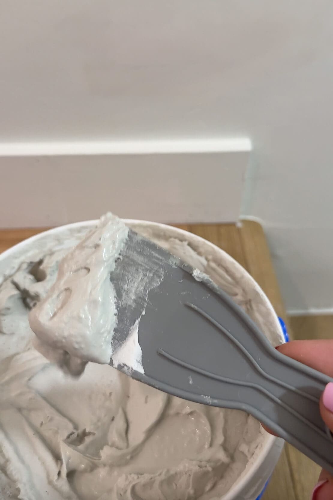 Close-up of joint compound on a gray putty knife, prepped for ceiling patching