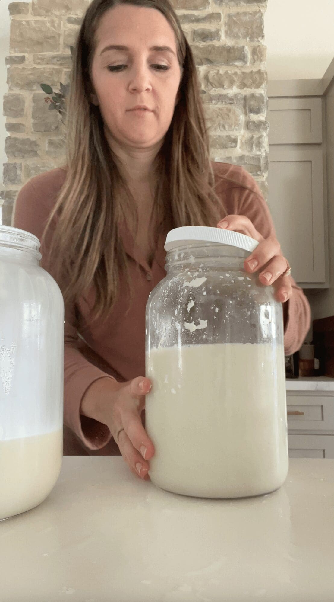 Putting a lid on a large glass jar while making a homemade probiotic drink.