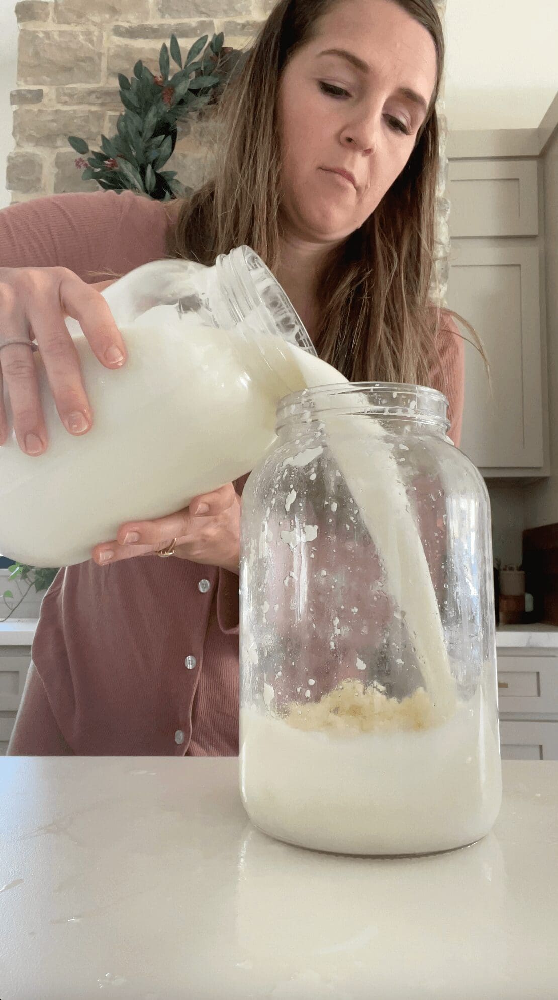 Pouring fresh milk into a jar to prepare for fermentation.