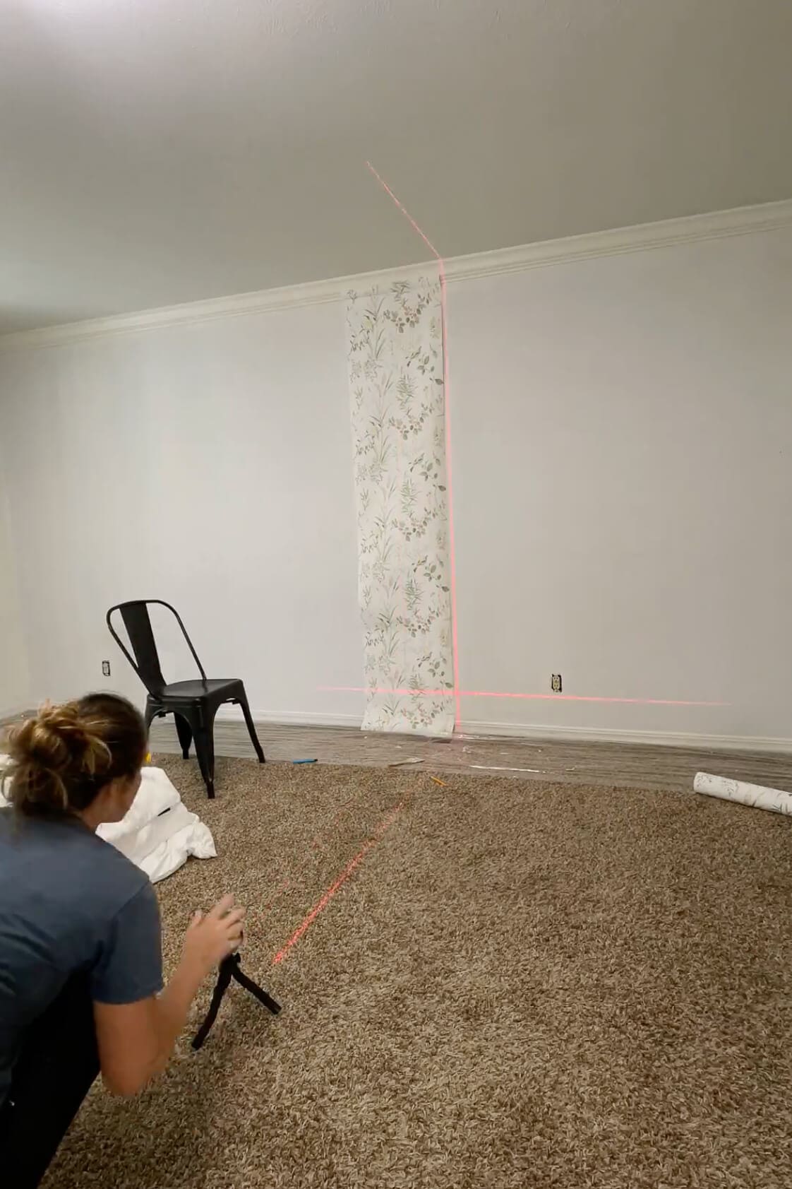 Adjusting a laser level while installing the first panel of traditional wallpaper