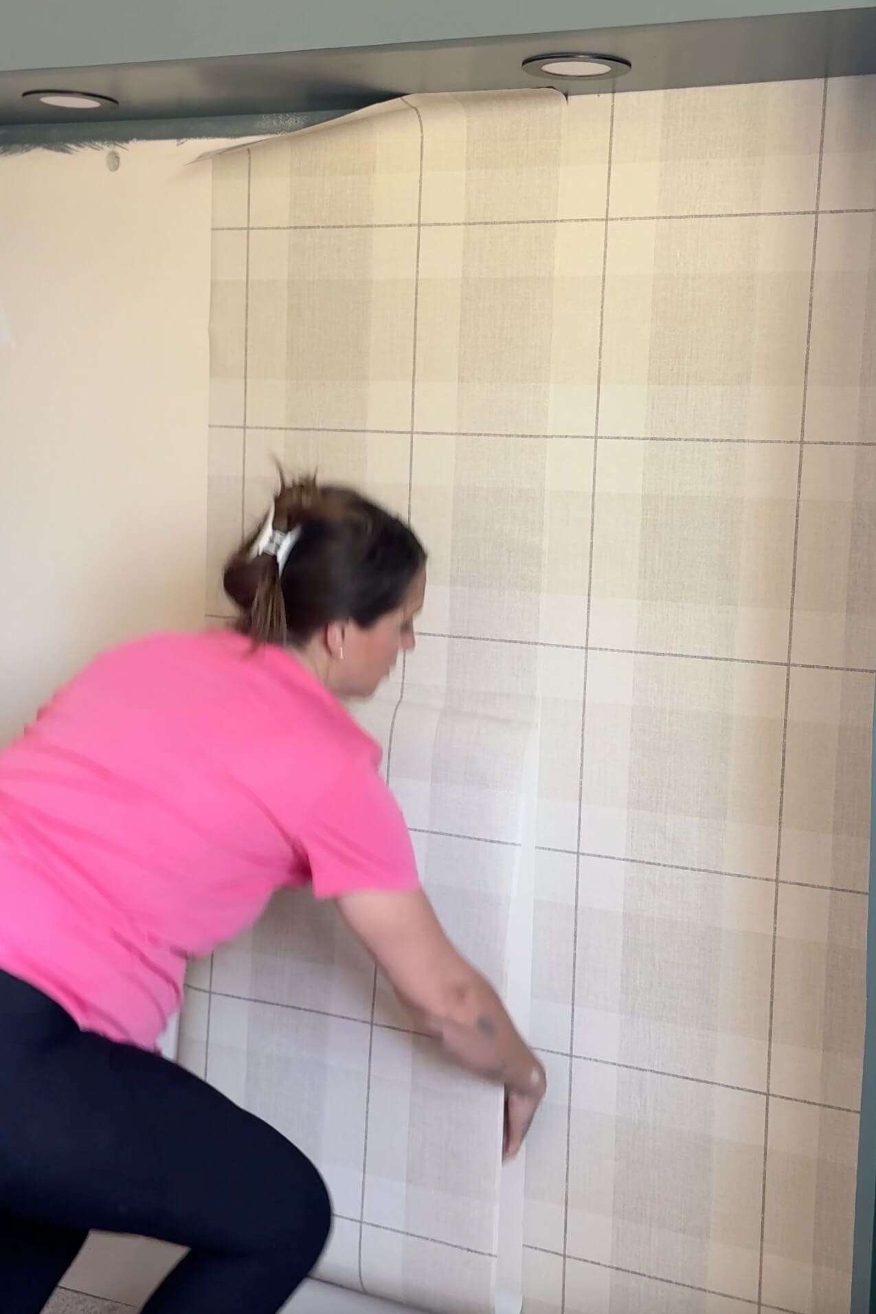 Lining up the second panel of plaid peel and stick wallpaper to match the pattern along the wall.