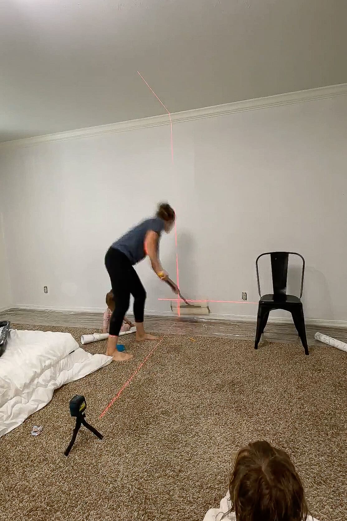 Applying paste to the wall using a roller, guided by a vertical laser level line