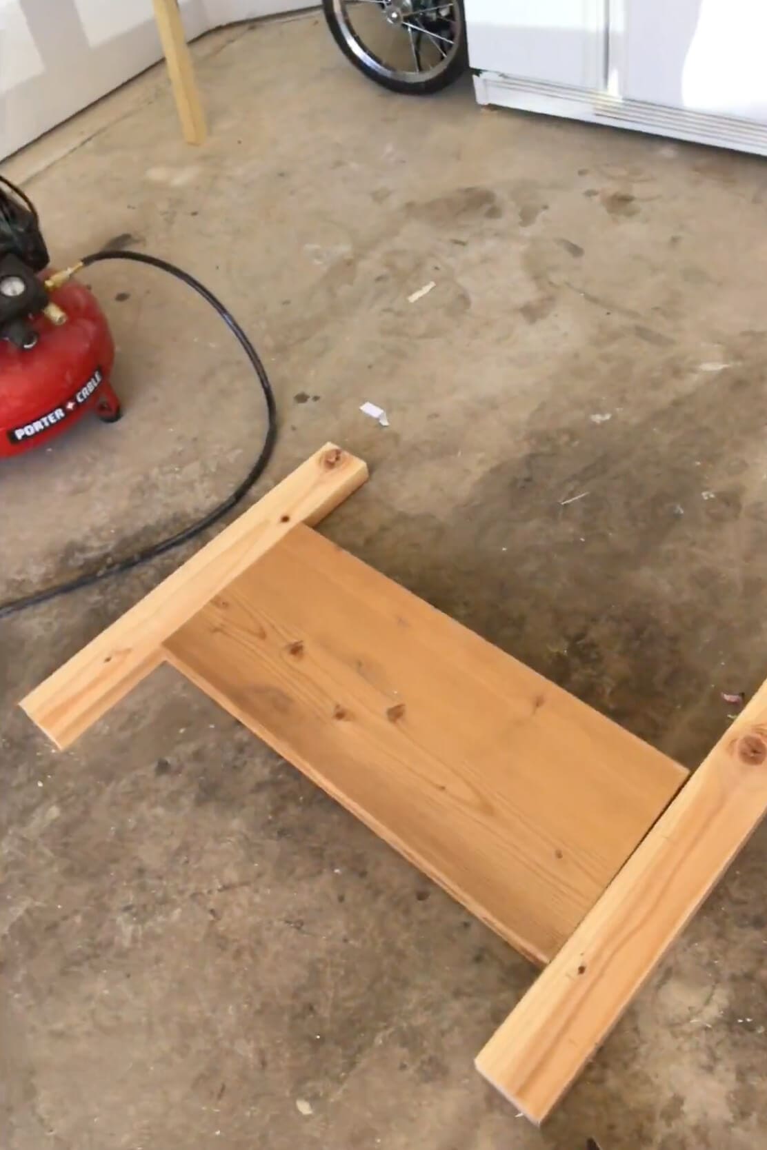 First frame pieces coming together on the garage floor during the build of a simple wooden kids bed.