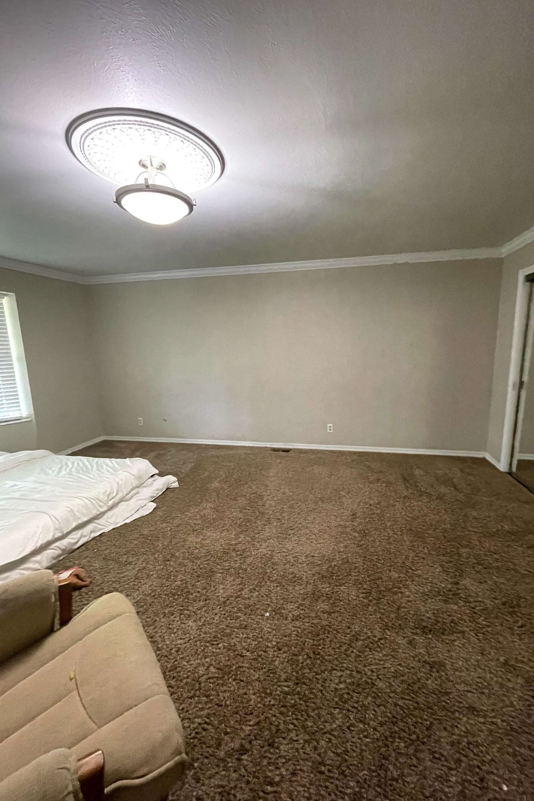 Empty bedroom with beige walls, crown molding, and carpeted floors