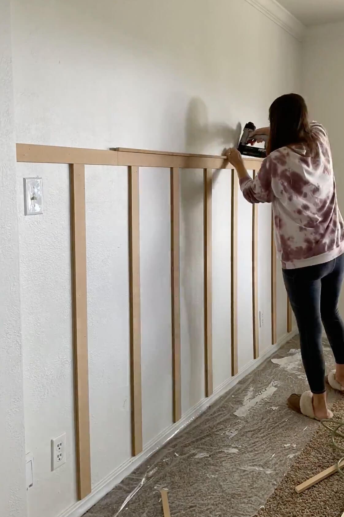 Progress shot of a DIY batten wall with vertical boards evenly spaced and the top board being secured into place.