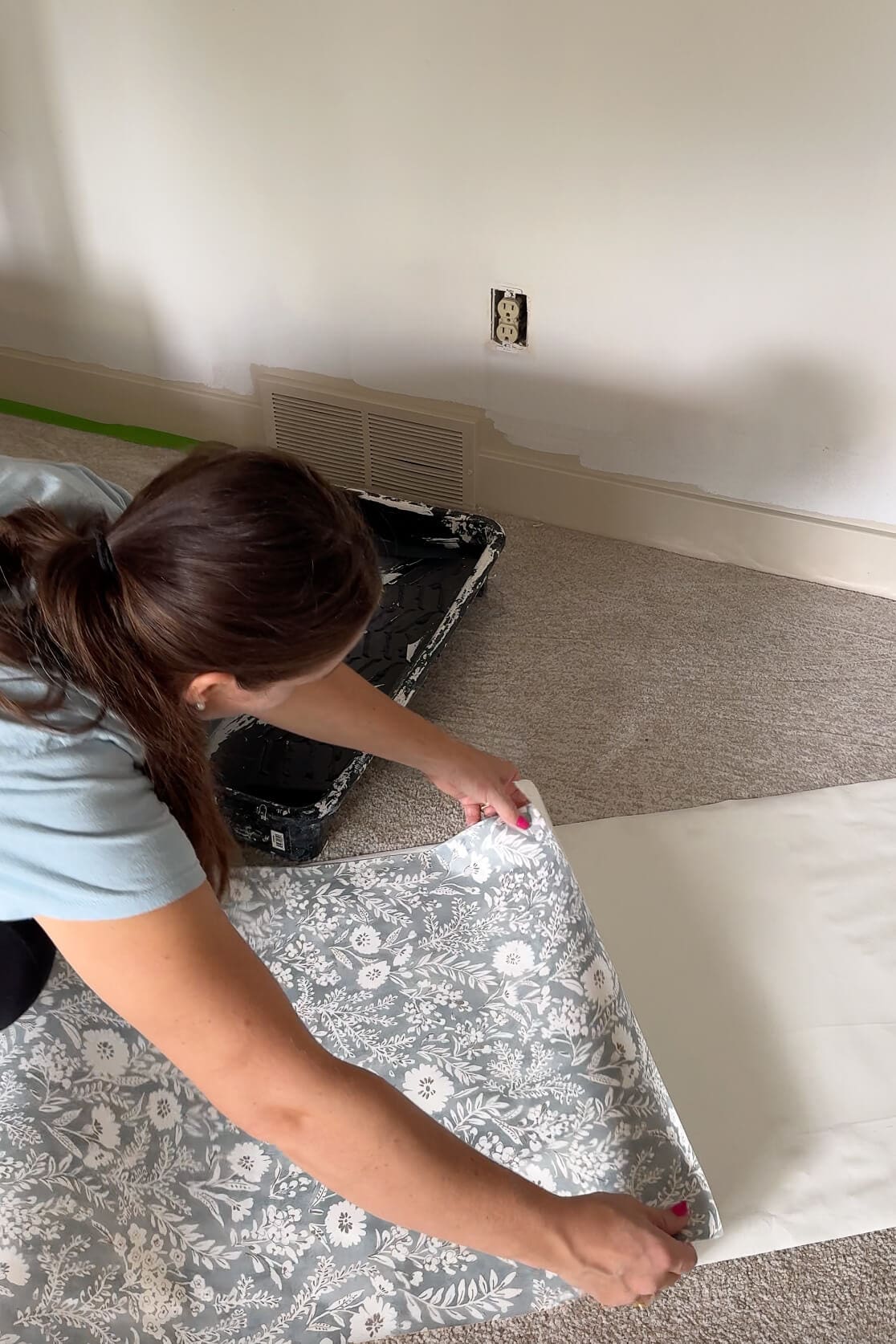 Woman gently folding floral wallpaper in on itself to start the booking process after activation.