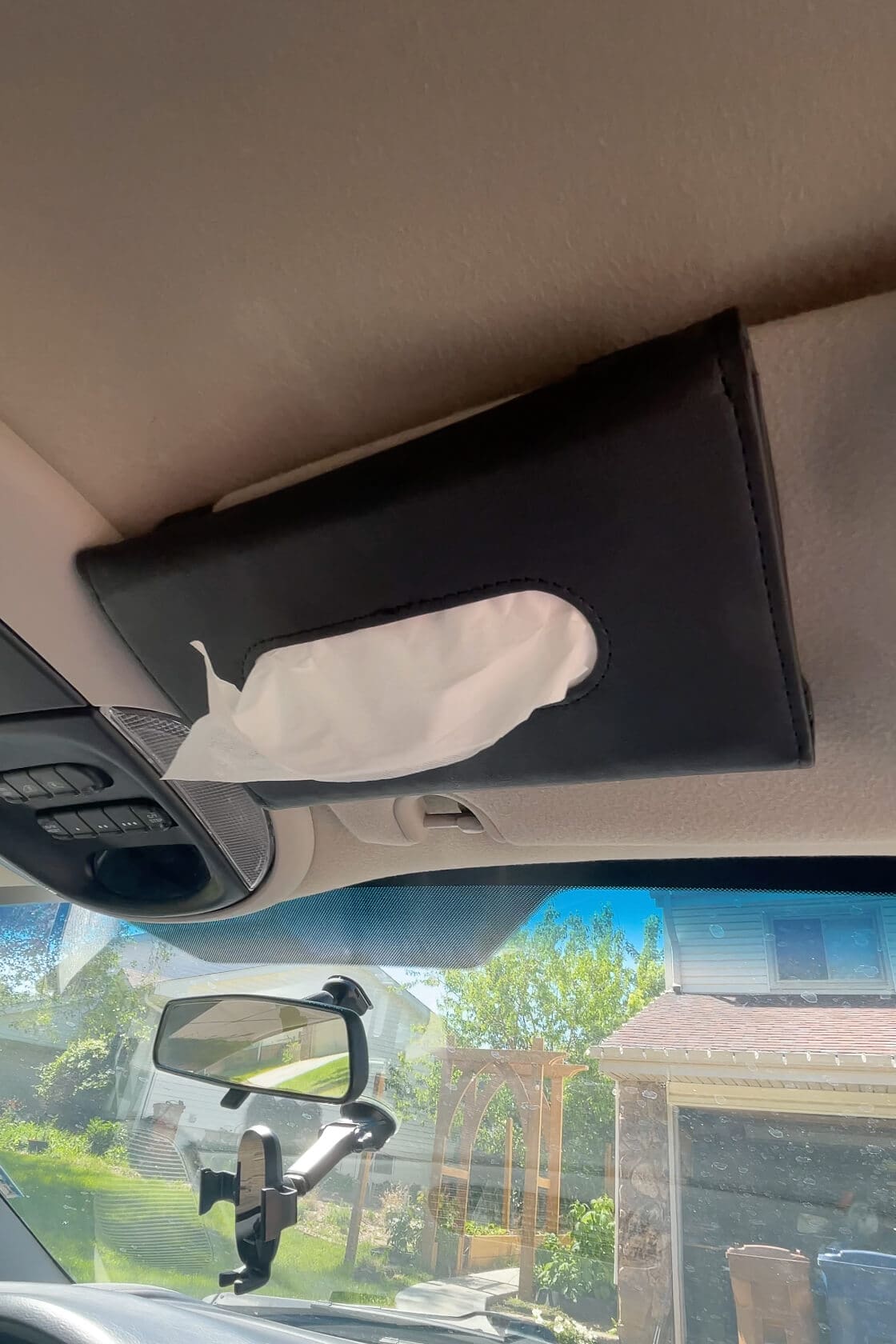 Black leather tissue holder clipped to the car’s sun visor for easy access during road trips or daily drives.