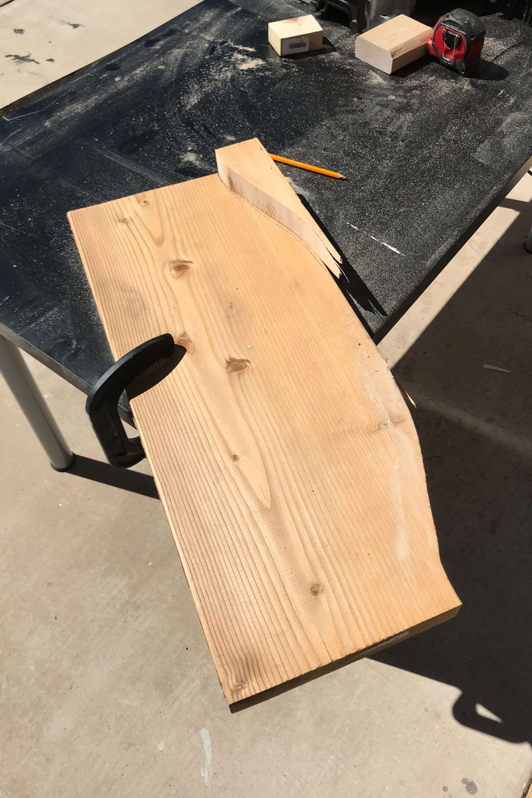 Shaping a scrap wood board with a jigsaw during the early stages of a DIY wood project.