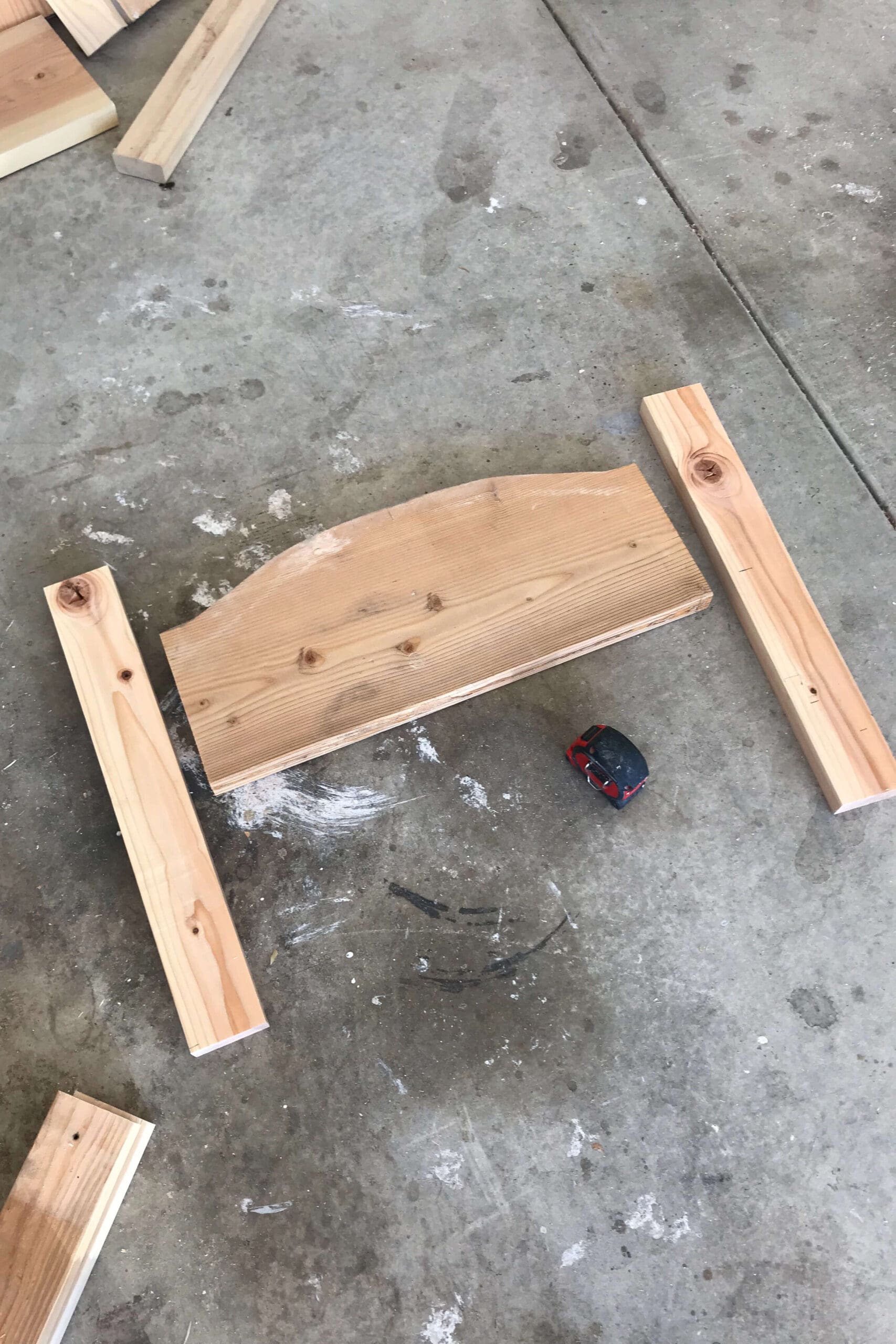 Dry fitting the headboard with scrap wood pieces and a measuring tape during the early stages of a DIY bed frame build.