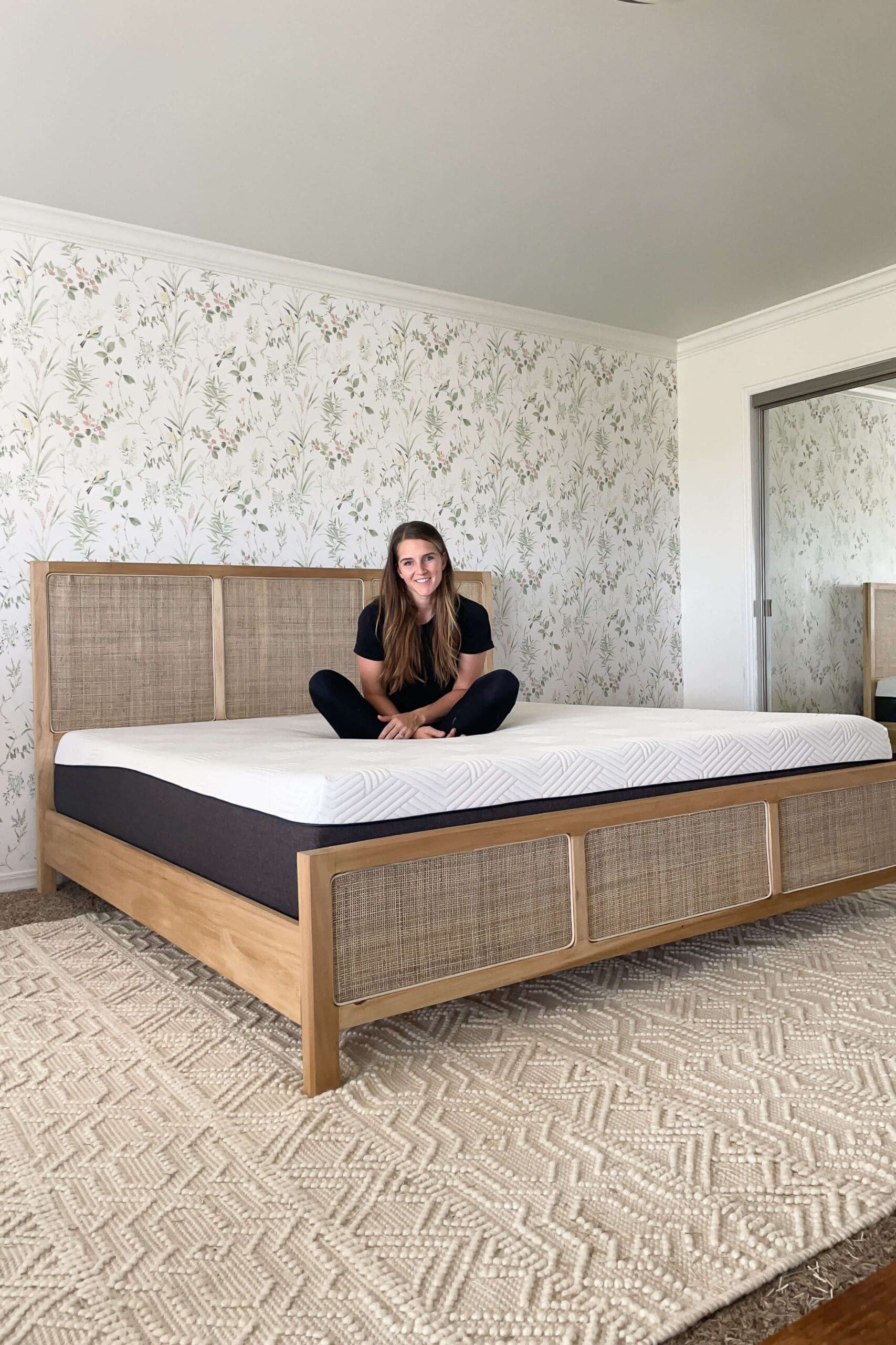 Finished bedroom with botanical traditional wallpaper behind a woven wood bed frame